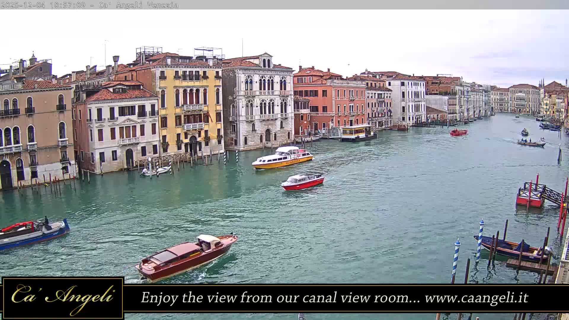 A busy Venetian canal, lined with colorful historic buildings, is traversed by numerous boats under a bright, overcast sky.
