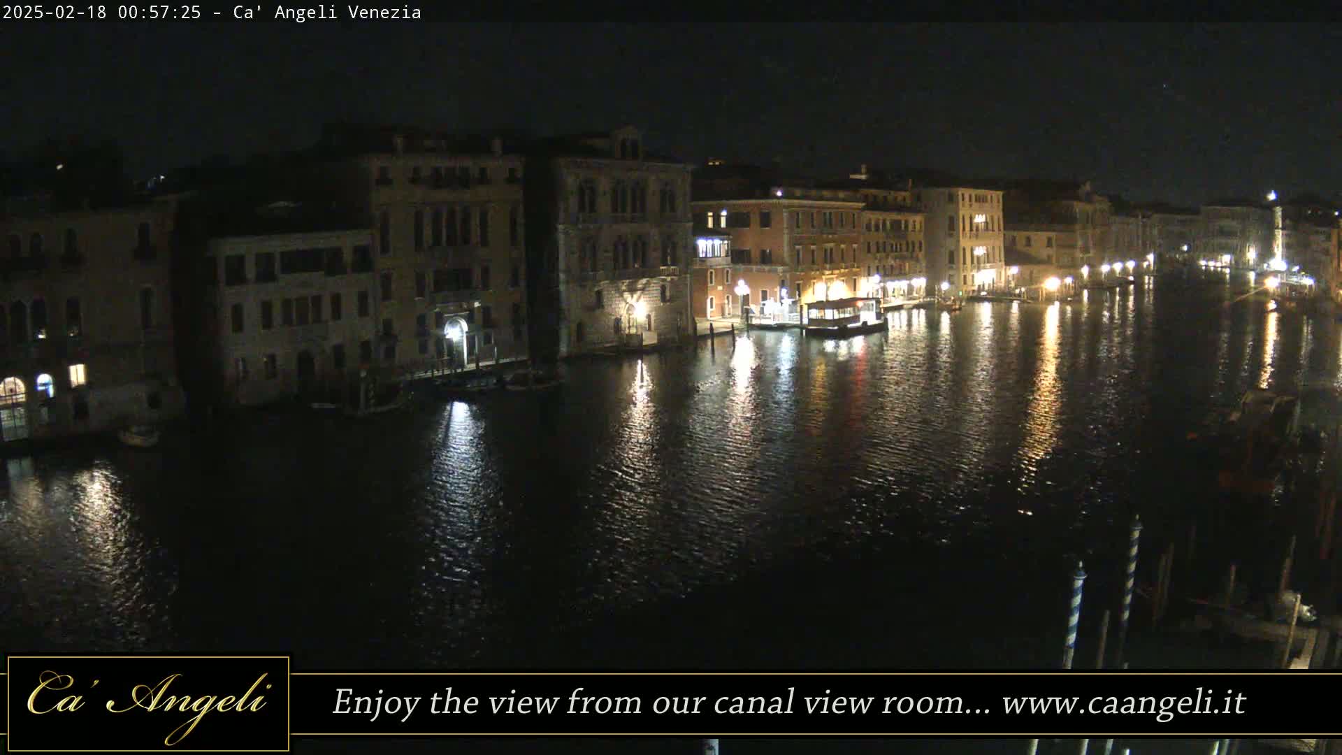 A nighttime view of a canal in Venice, lined with buildings reflecting in the dark water.