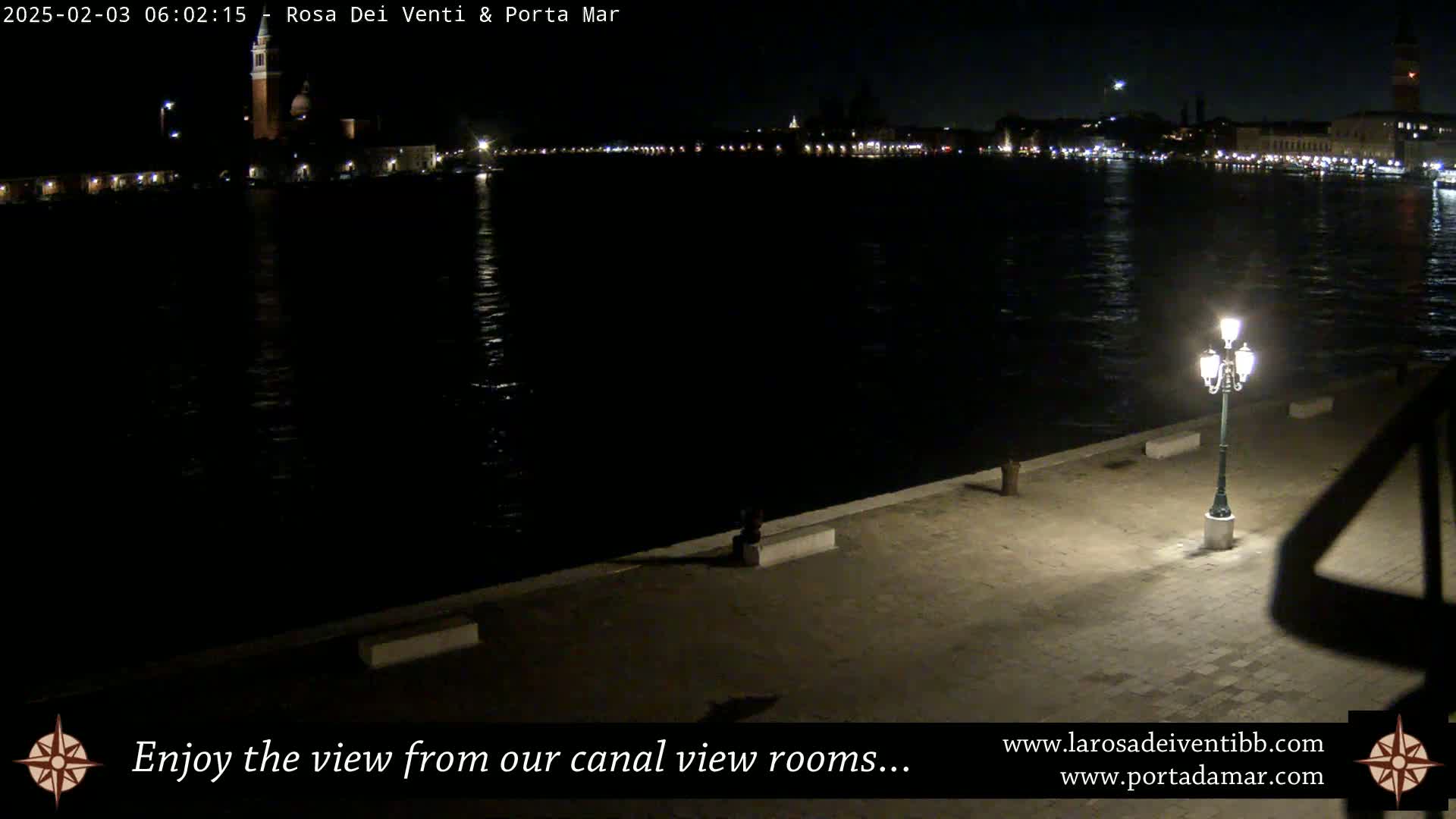 A nighttime view of a canal in Venice, Italy, with city lights reflecting on the dark water.