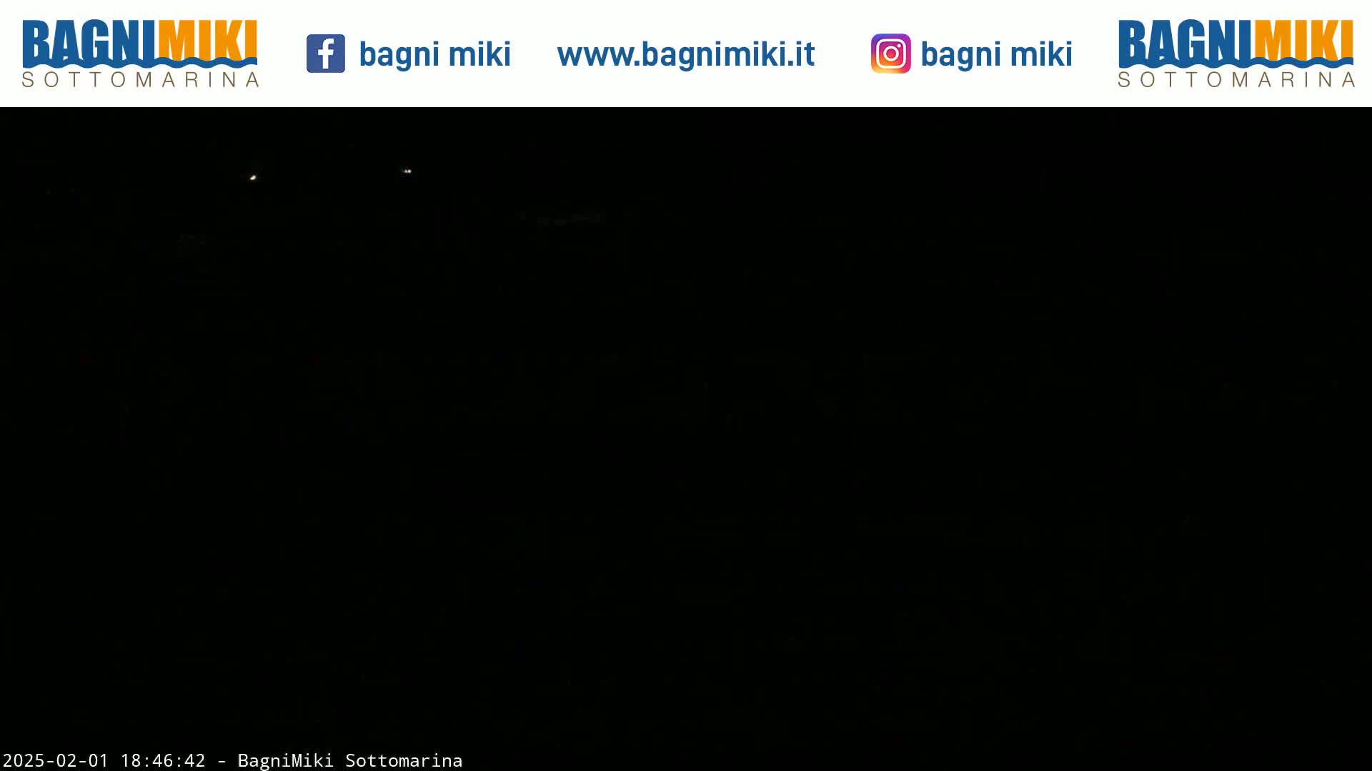 A completely dark nighttime scene shows two faint lights in the distance.