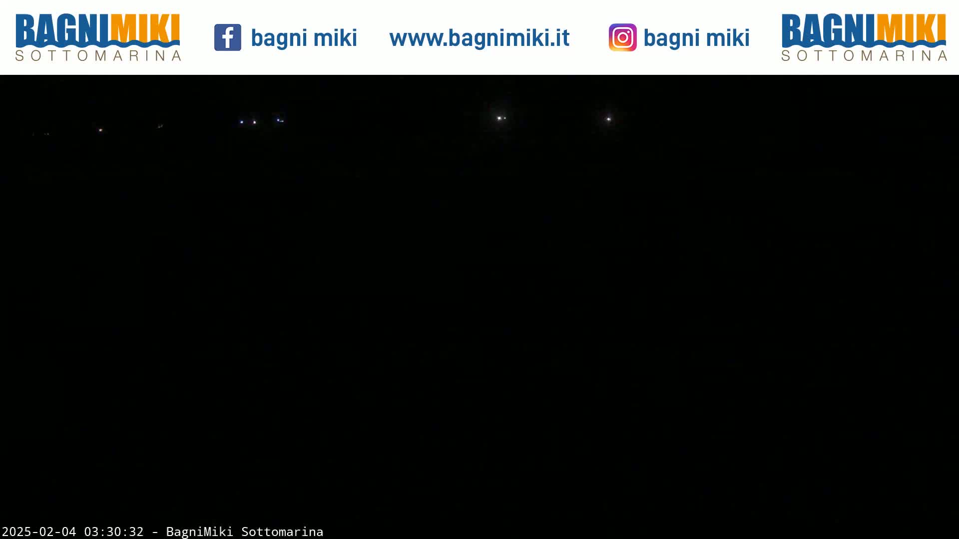 A dark, nighttime scene shows a few faint lights in the distance under a clear, dark sky.