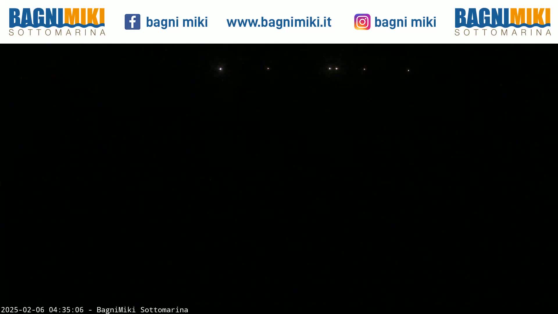 A dark nighttime scene shows several faint lights in the distance.