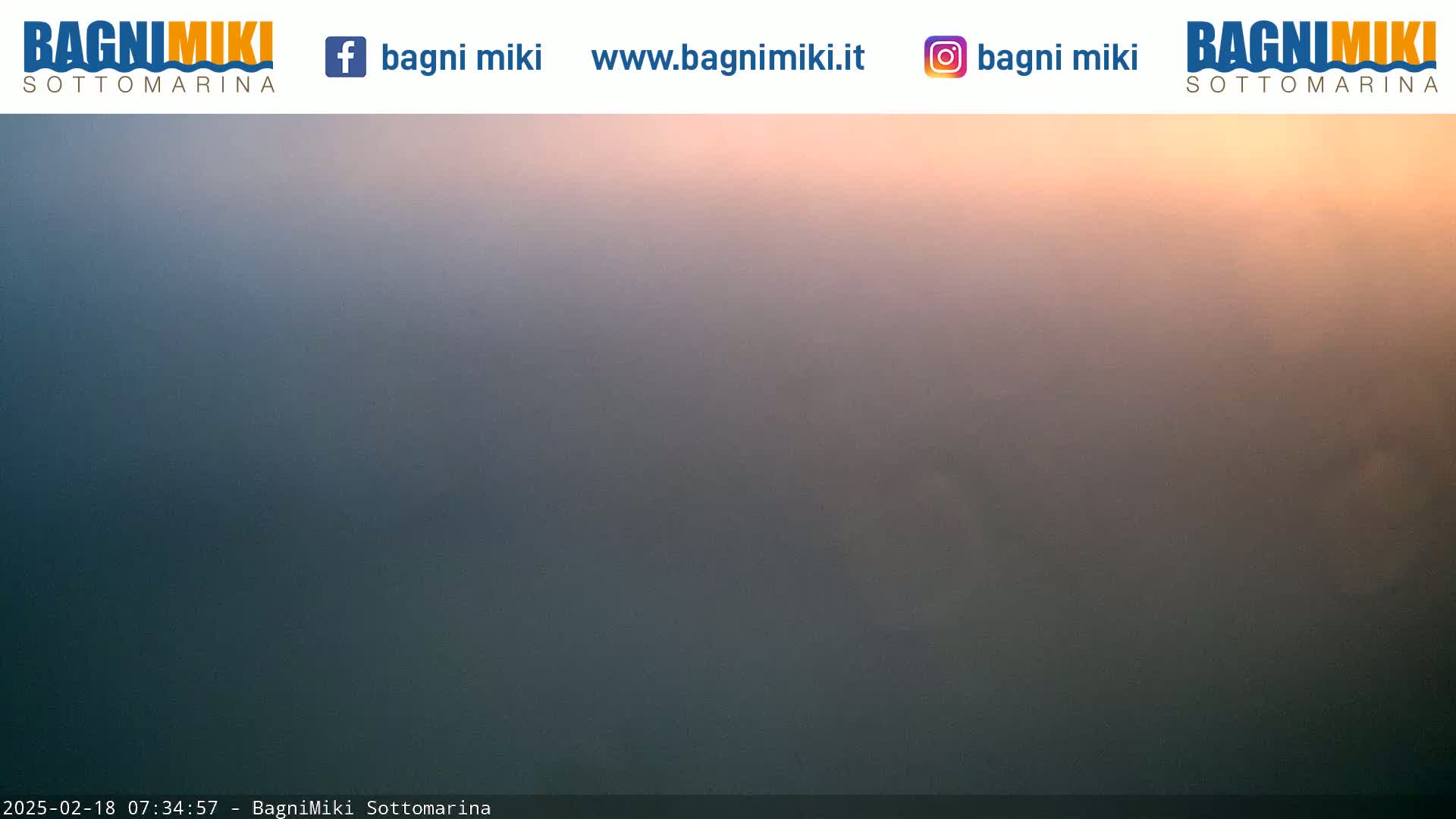 A hazy, peach-colored sunrise is visible over a dark, indistinct landscape.