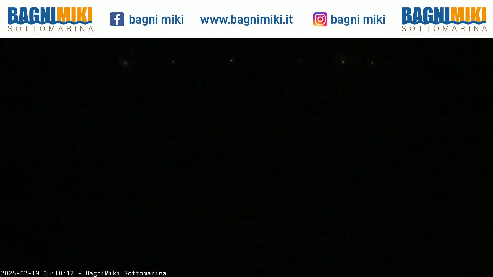 A nighttime, dark image shows a few faint lights in the distance.