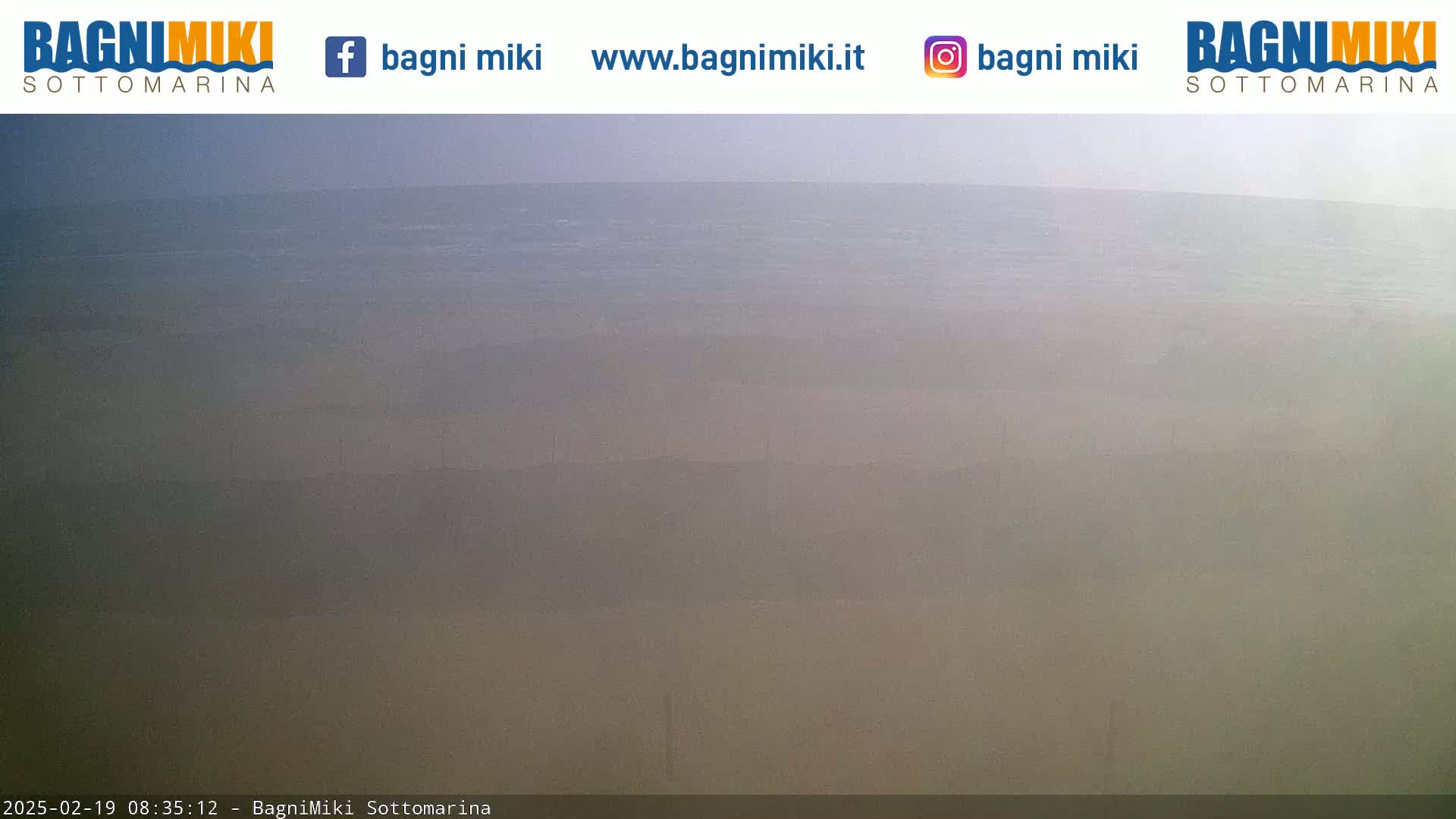 A hazy, overcast view of a calm body of water stretching to the horizon.