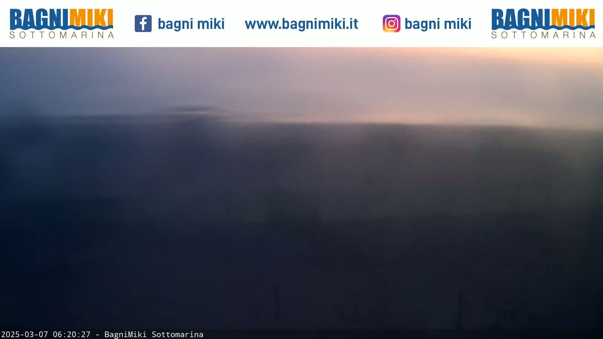 A hazy, dark-colored landscape is visible under a pale, pinkish-purple sky at dawn or dusk.