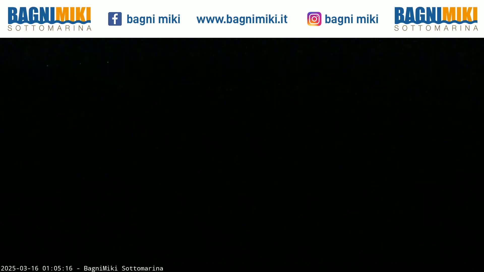 The image shows a completely black nighttime scene with a few faint, distant lights.