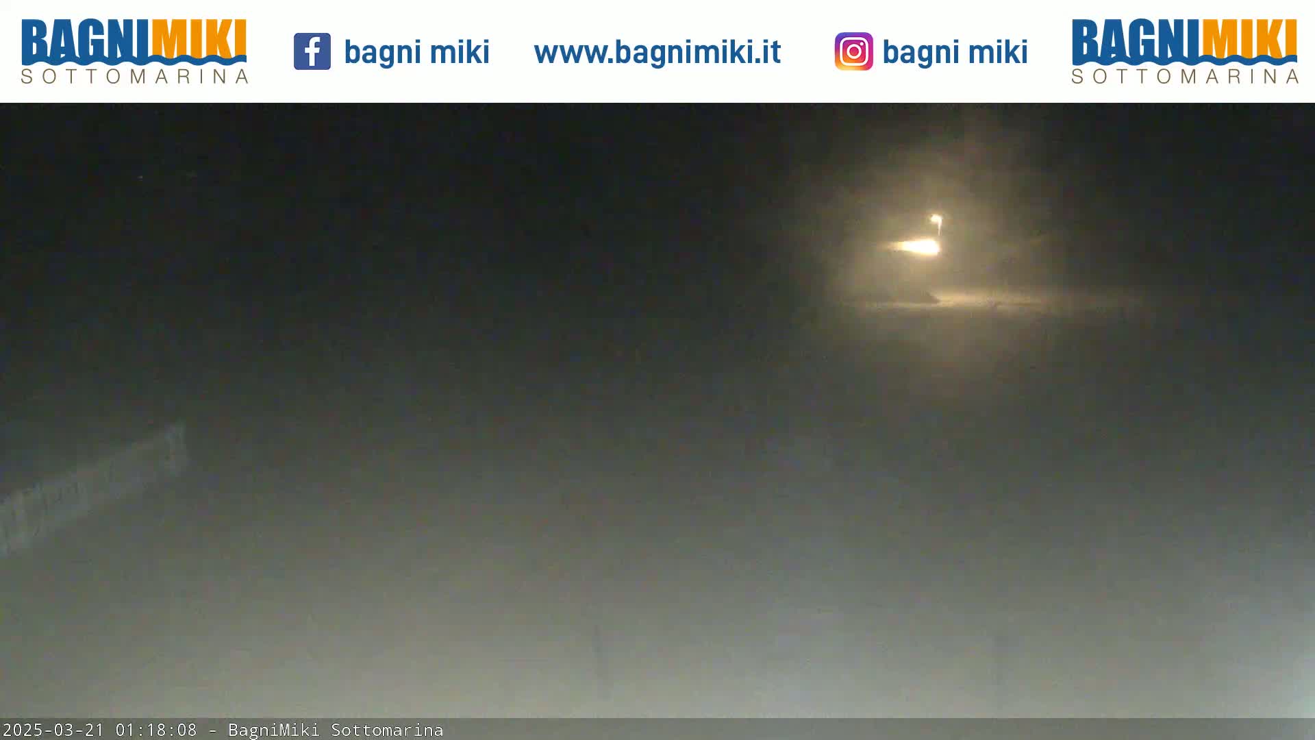 A nighttime, hazy view shows a bright light source in the distance.