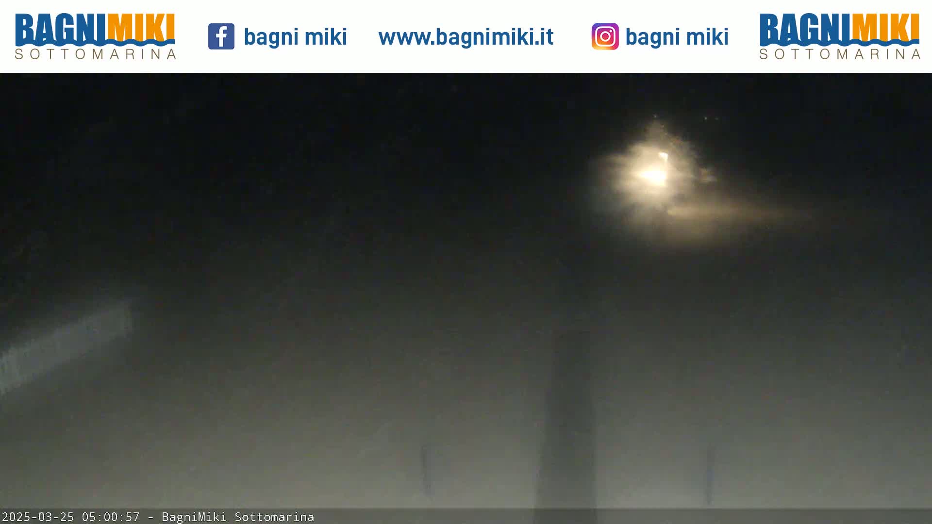 A hazy night scene is illuminated by a bright light source in the distance.