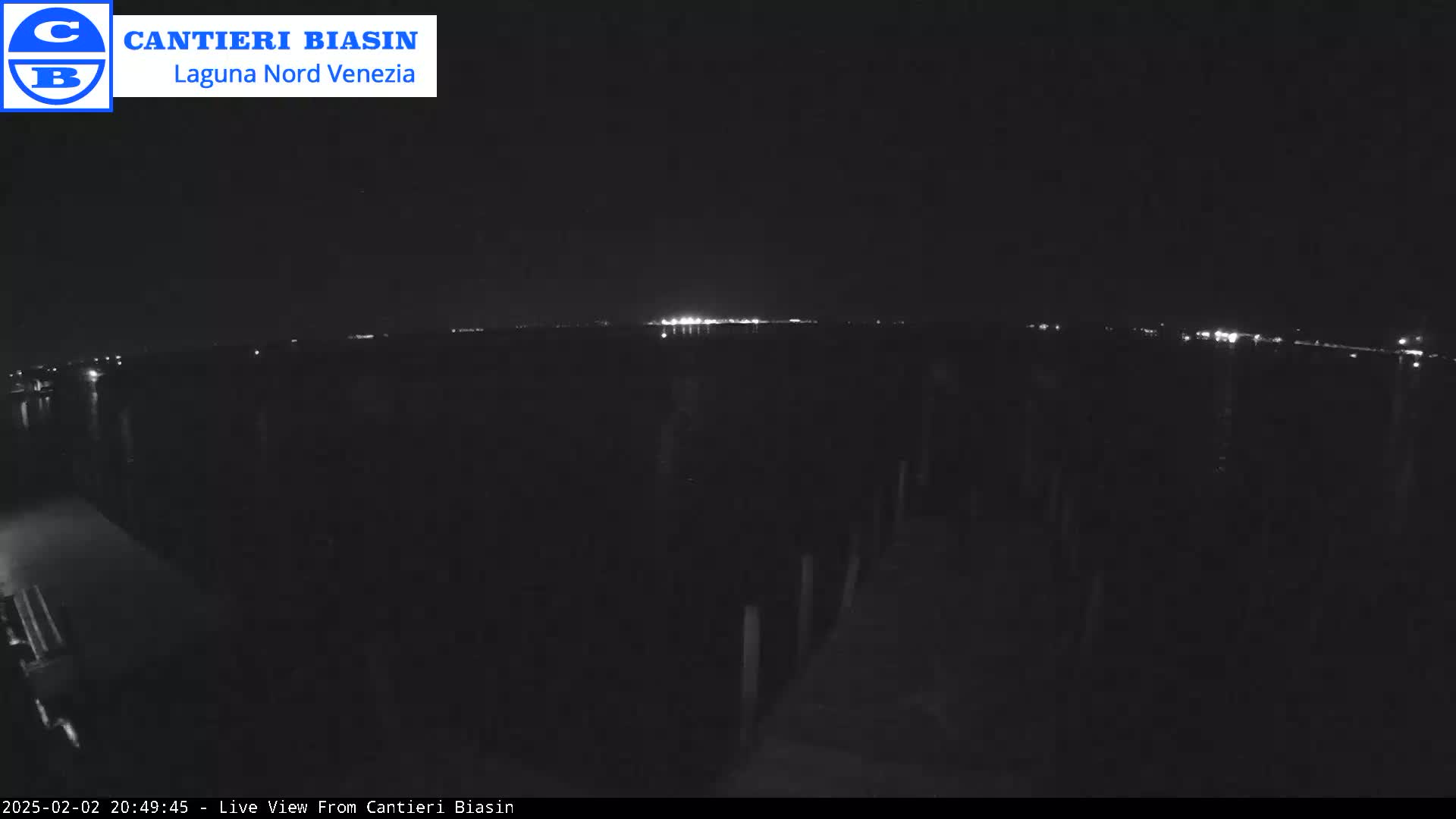 A nighttime view of a dark body of water with distant lights on the horizon.