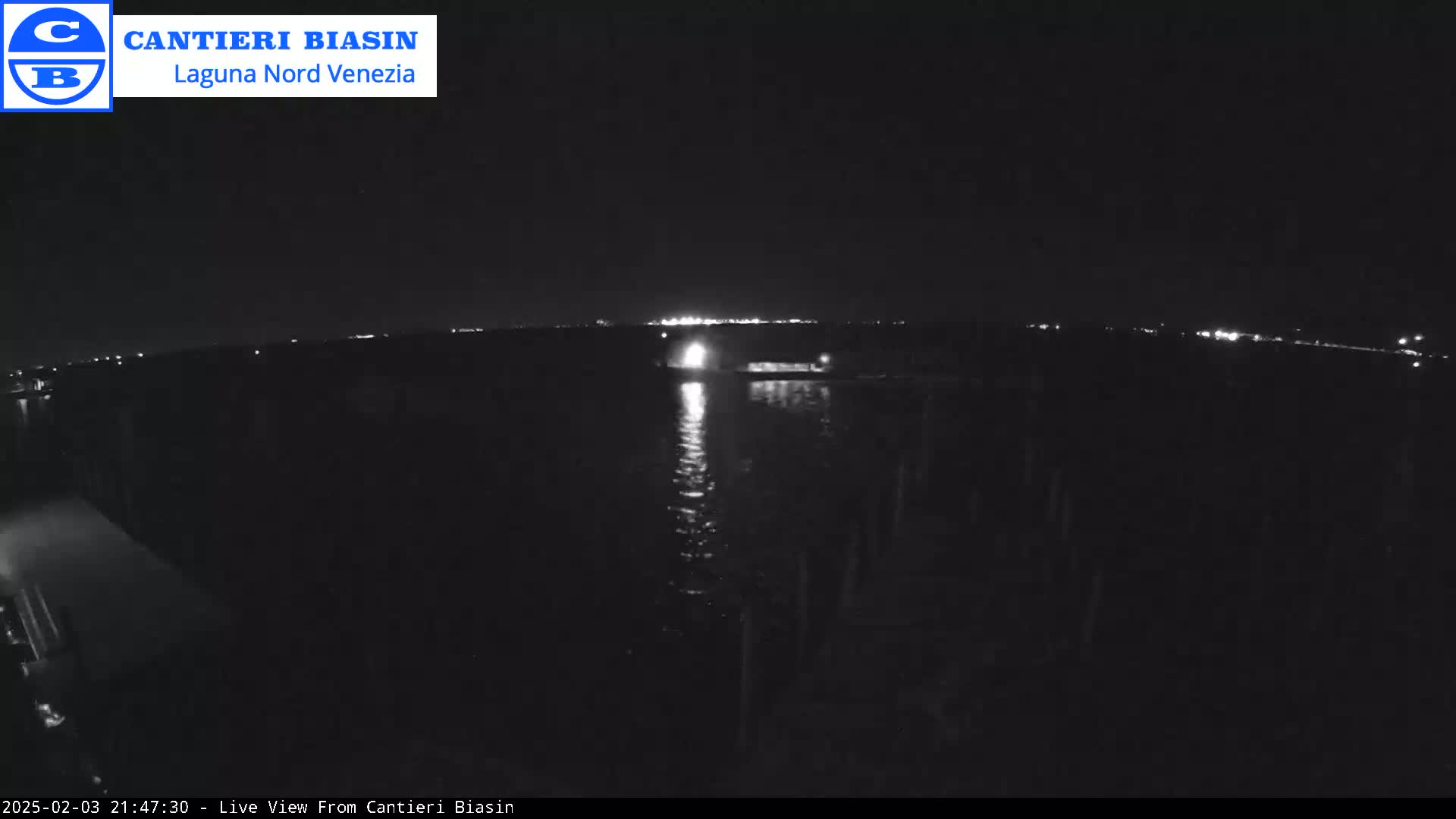 A nighttime view of a dark body of water reflecting lights from a distant shore.