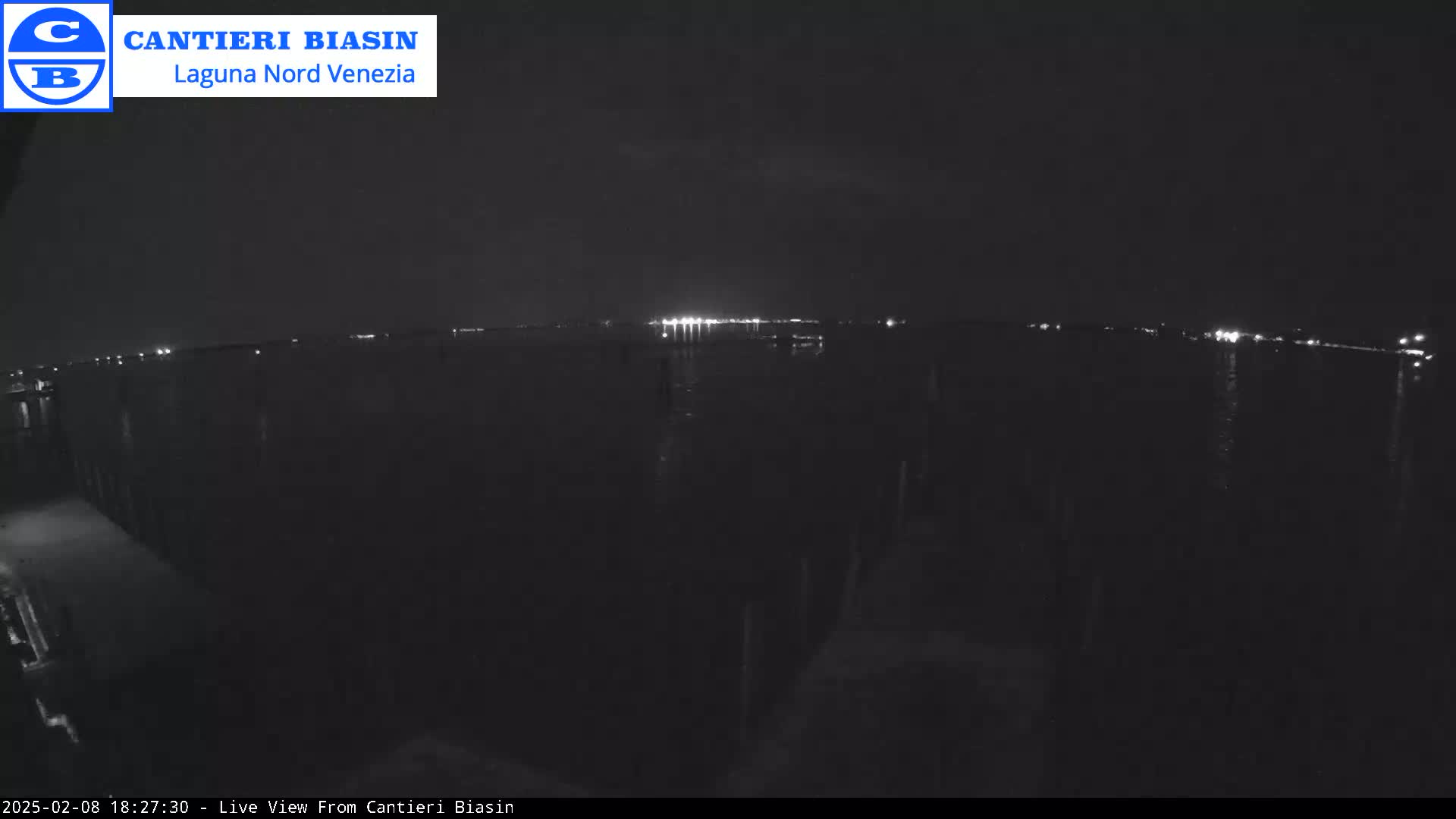 A nighttime, low-light view of a body of water with distant lights on the opposite shore.