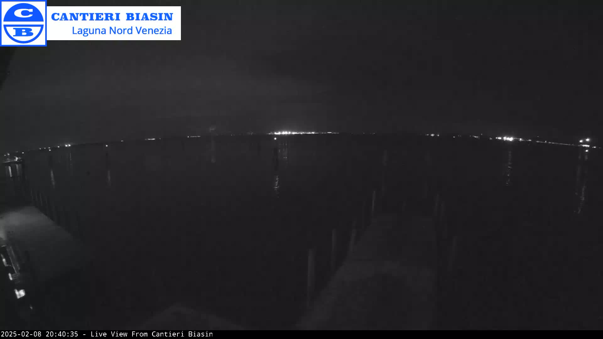 A nighttime view of a dark body of water with distant lights on the horizon.