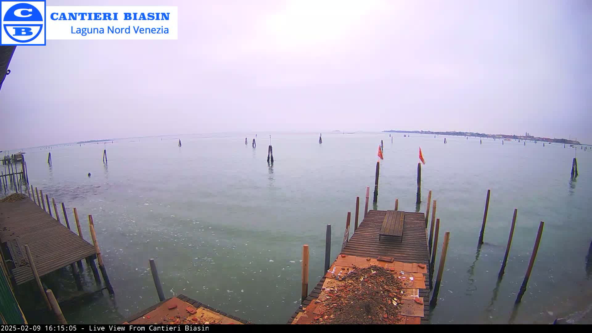 A tranquil body of water with numerous wooden posts and a small dock, under an overcast sky.