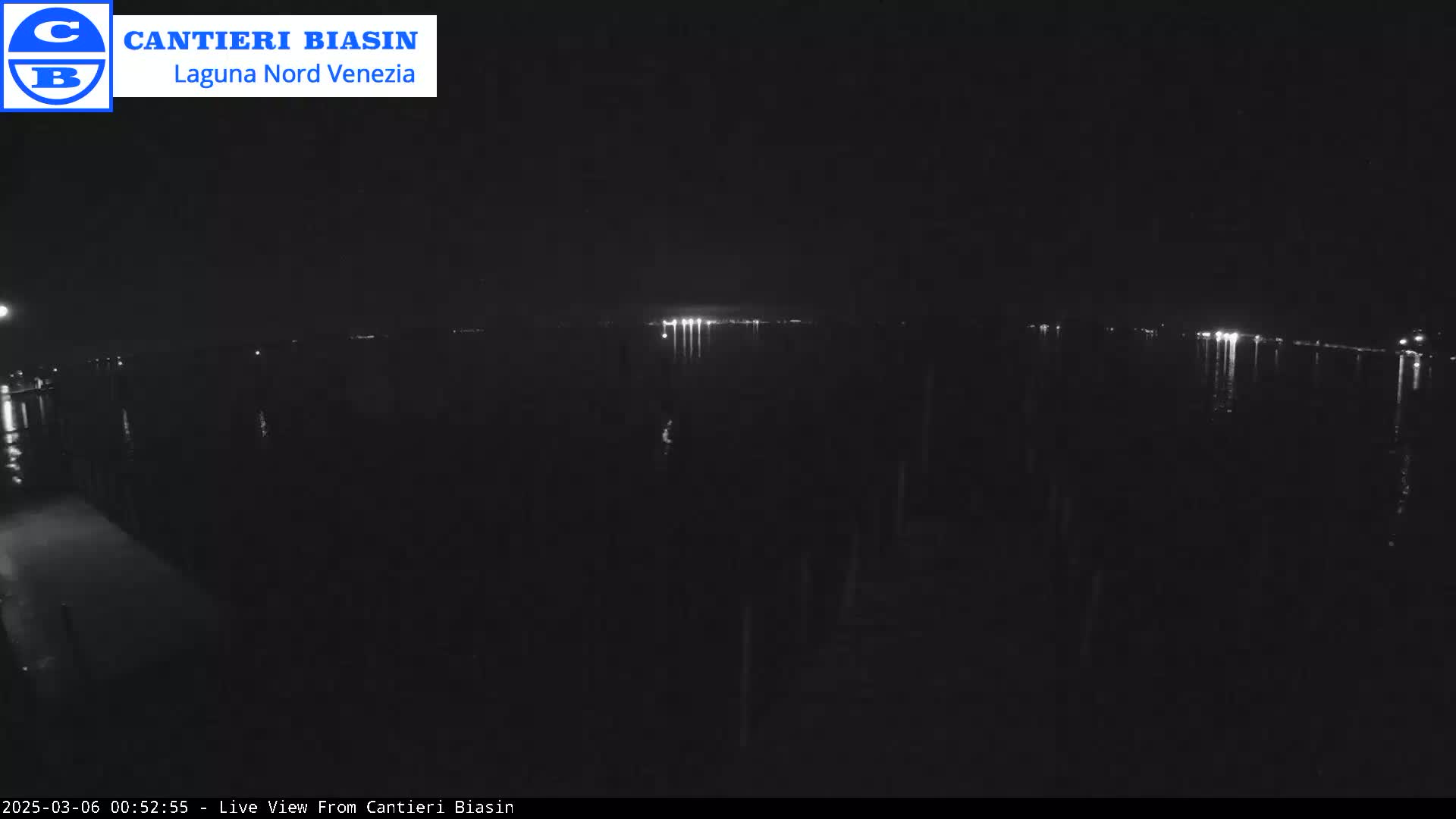 A dark, nighttime view of a body of water with distant lights reflecting on the surface.