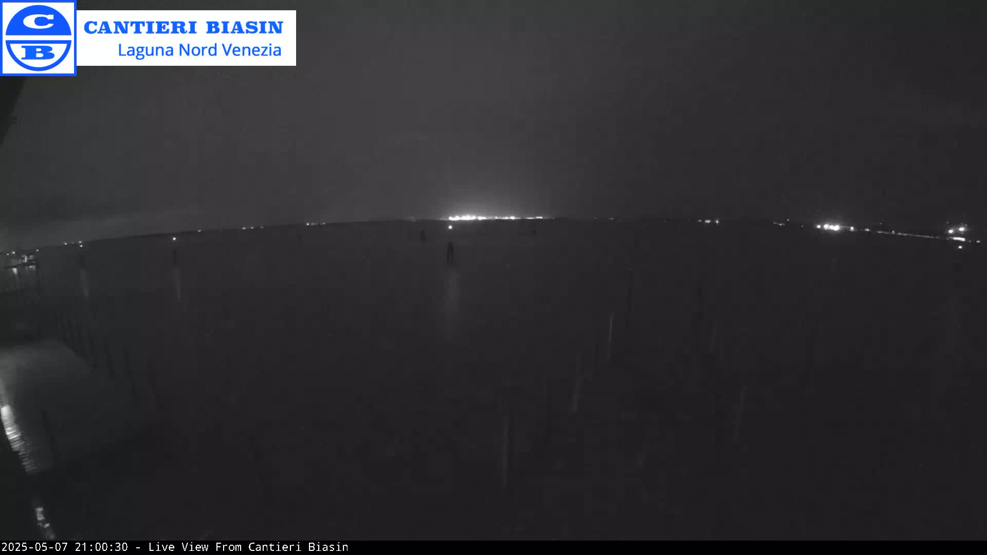 A nighttime, dark view of a body of water with a distant line of lights visible on the horizon.