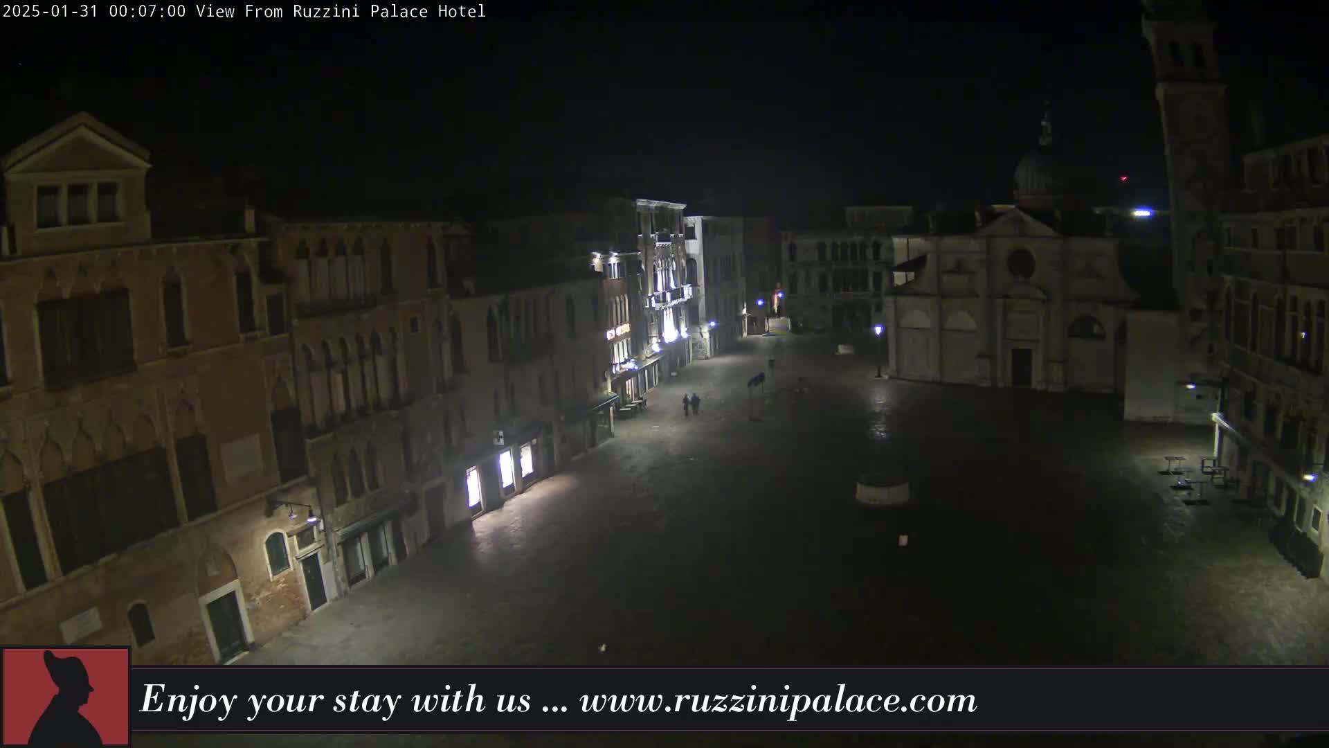 A nighttime, aerial view of a dimly lit, empty Venetian square, with several buildings surrounding it.
