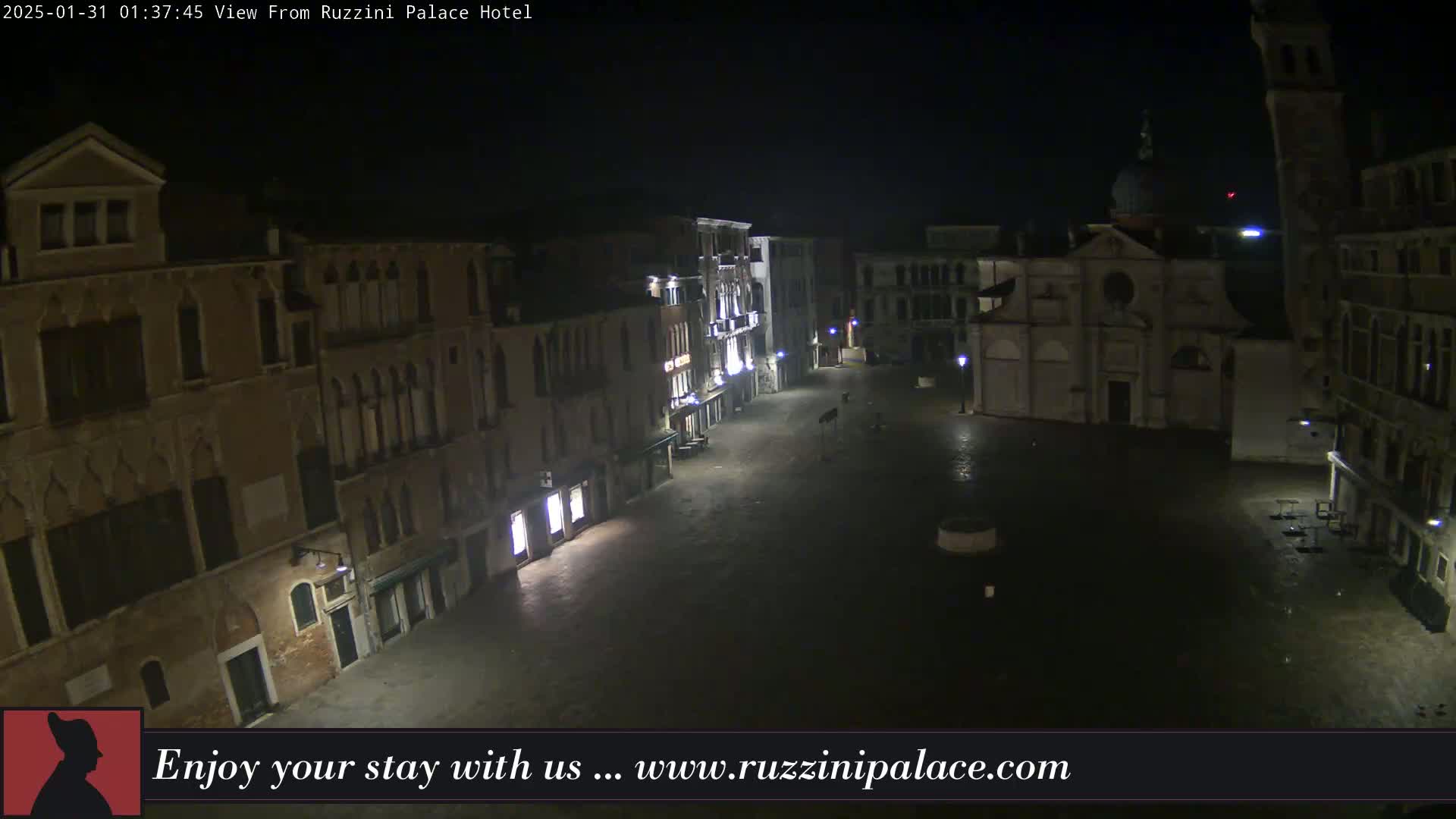A nighttime view of a deserted, cobblestone square in Venice, Italy, surrounded by old buildings under a dark, possibly overcast sky.