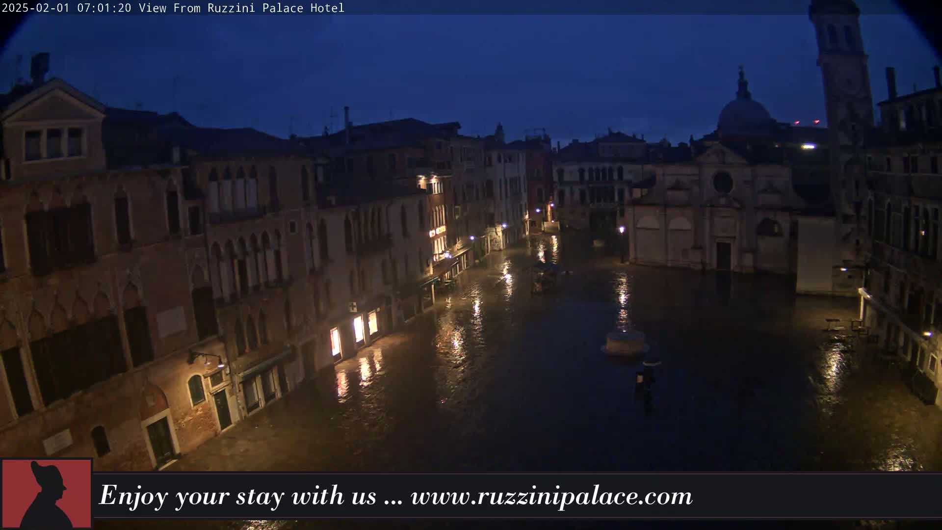 A nighttime view of a flooded Venetian square, surrounded by old buildings under a dark sky.