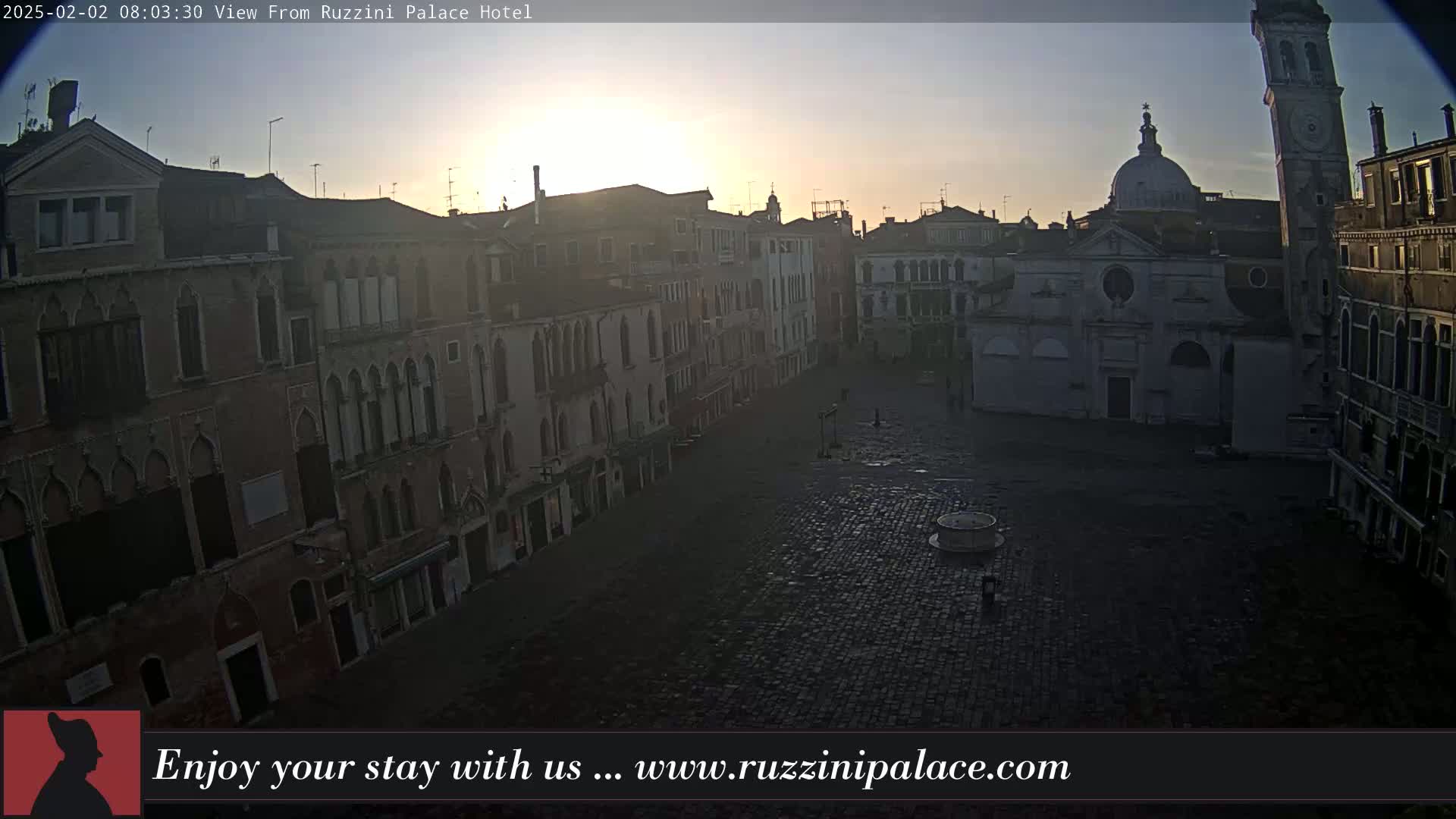 A sunrise illuminates an empty cobblestone square in Venice, surrounded by old buildings.