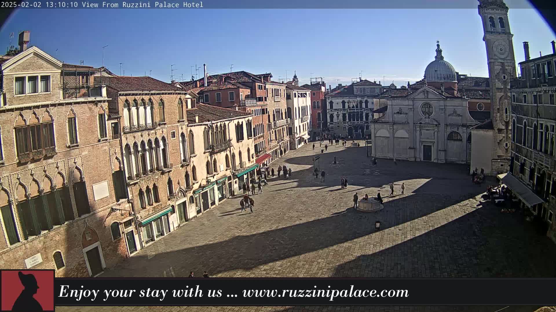 A sunny day reveals a large, mostly empty plaza in Venice, surrounded by historic buildings, with a few people scattered throughout.