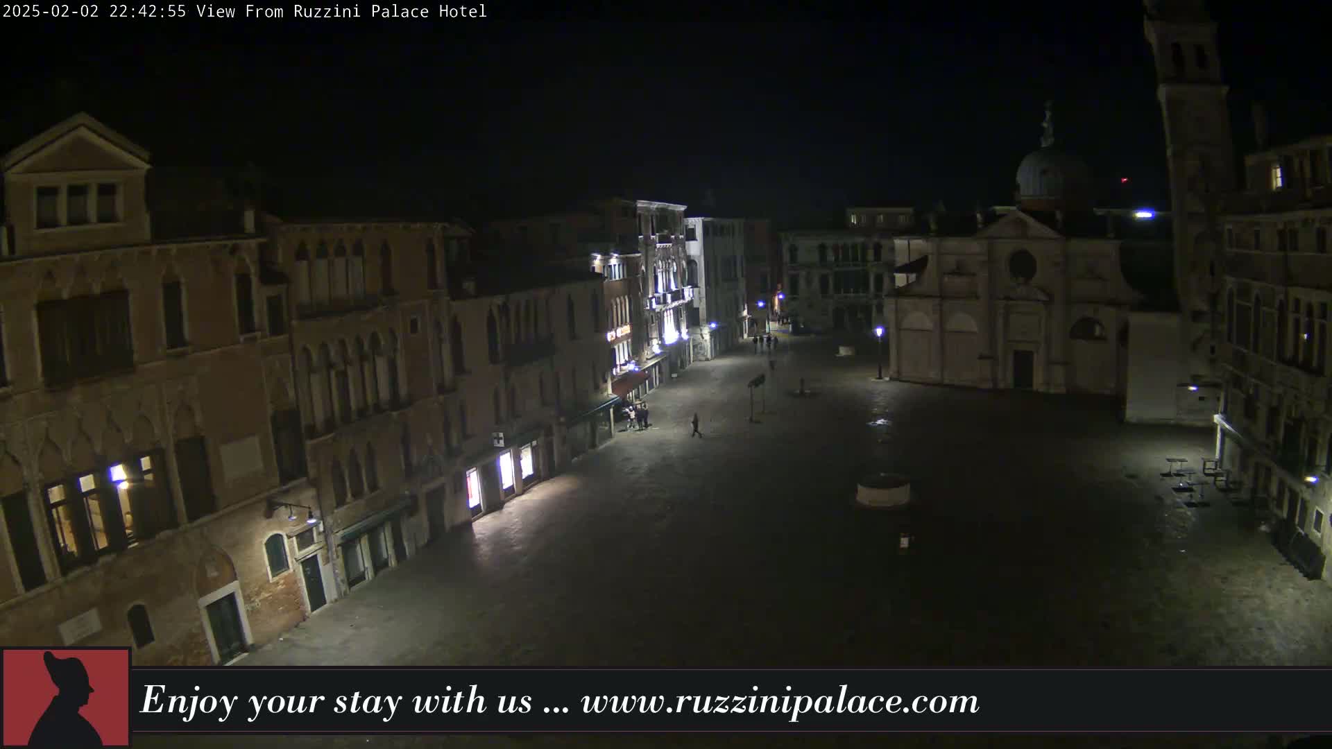 A nighttime, high-angle view shows an empty cobblestone square in Venice, Italy, surrounded by old buildings.