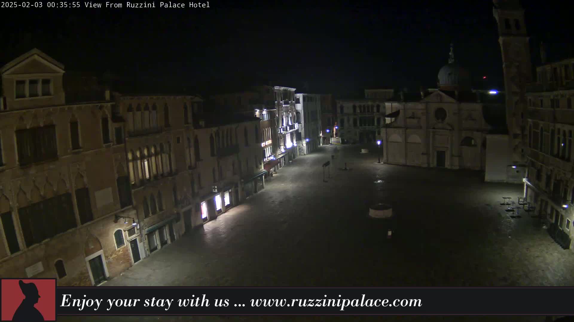 A nighttime view of a mostly empty cobblestone square in Venice, Italy, surrounded by old buildings under a clear, dark sky.