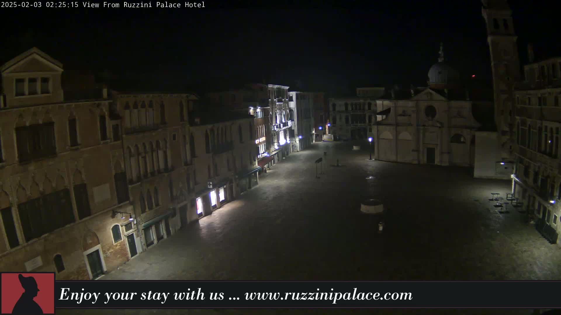 A nighttime, high-angle view of a dimly lit, empty square in Venice, surrounded by old buildings.