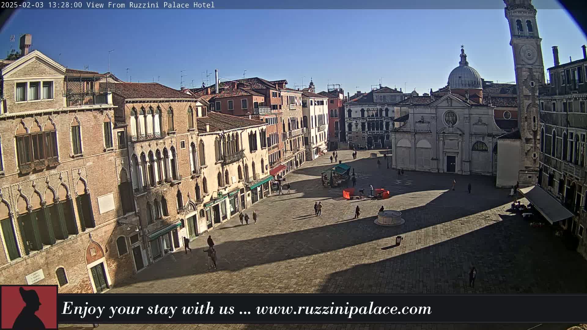 A sunny, spacious Venetian square is seen from above, surrounded by historic buildings, with a few people sparsely scattered throughout.