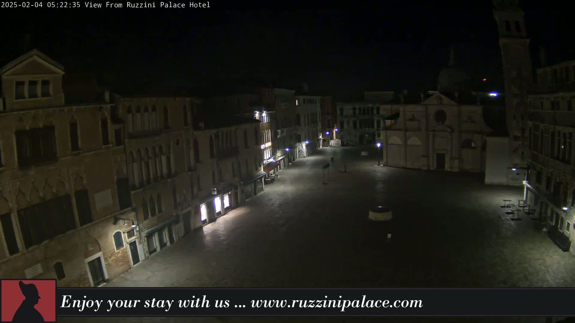 A nighttime, dimly lit, empty square in Venice, surrounded by old buildings, is seen from above.