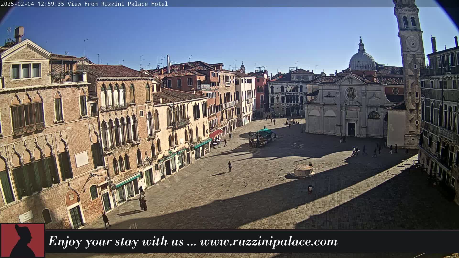 A sunny, mostly empty Venetian square is surrounded by historic buildings, including a church with a dome and a tall leaning tower.