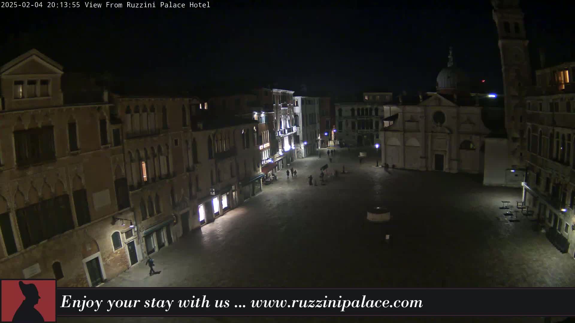 A nighttime, high-angle view of a dimly lit, empty square in Venice, surrounded by old buildings.