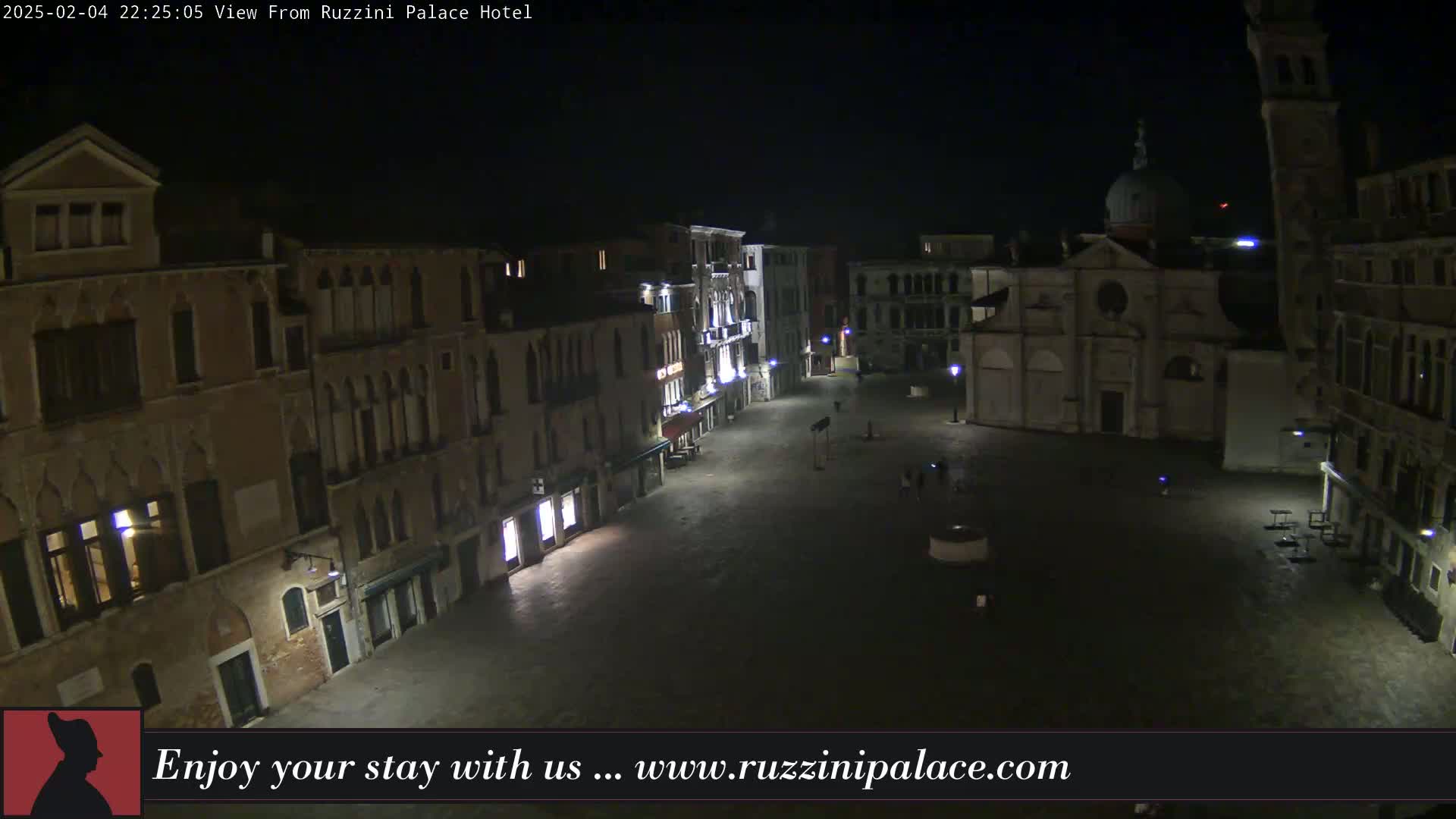 A nighttime view of a mostly empty square in Venice, surrounded by old buildings, under a clear, dark sky.