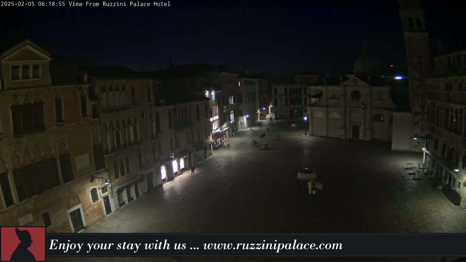 A nighttime, aerial view of a dimly lit, mostly empty square in Venice, surrounded by historic buildings.