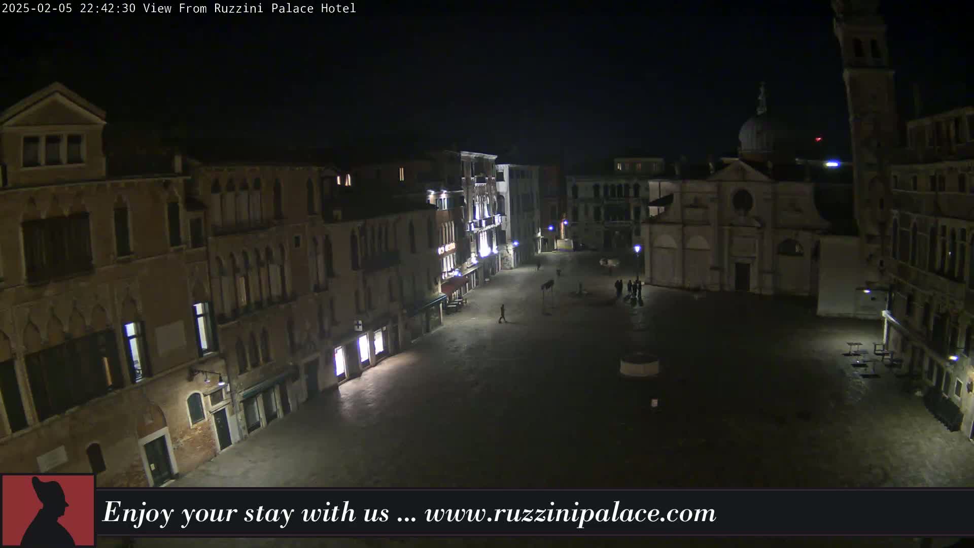 A nighttime view of a dimly lit, empty Venetian square surrounded by old buildings.