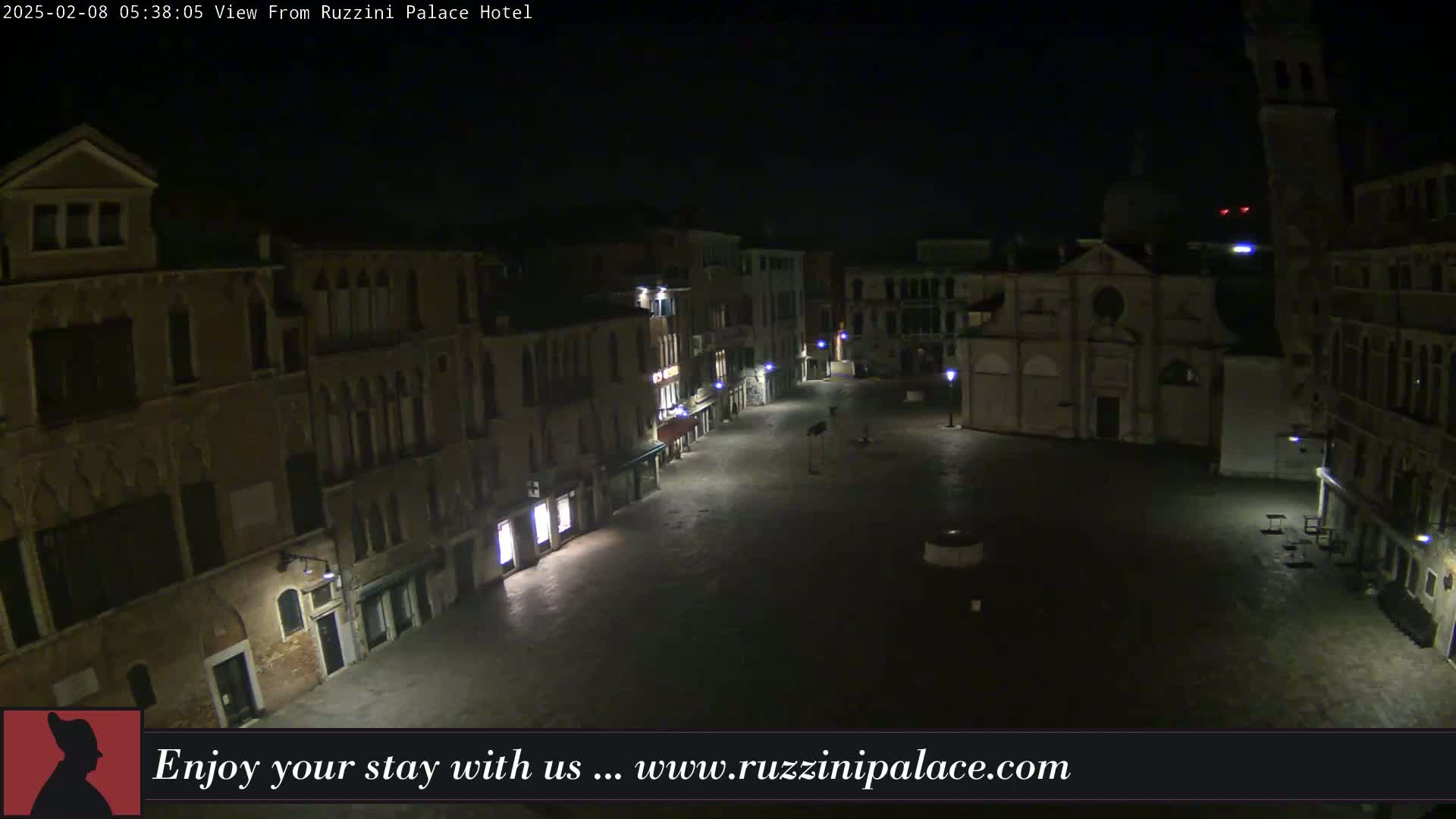 A nighttime, aerial view of a mostly empty cobblestone square in Venice, Italy, surrounded by historic buildings.