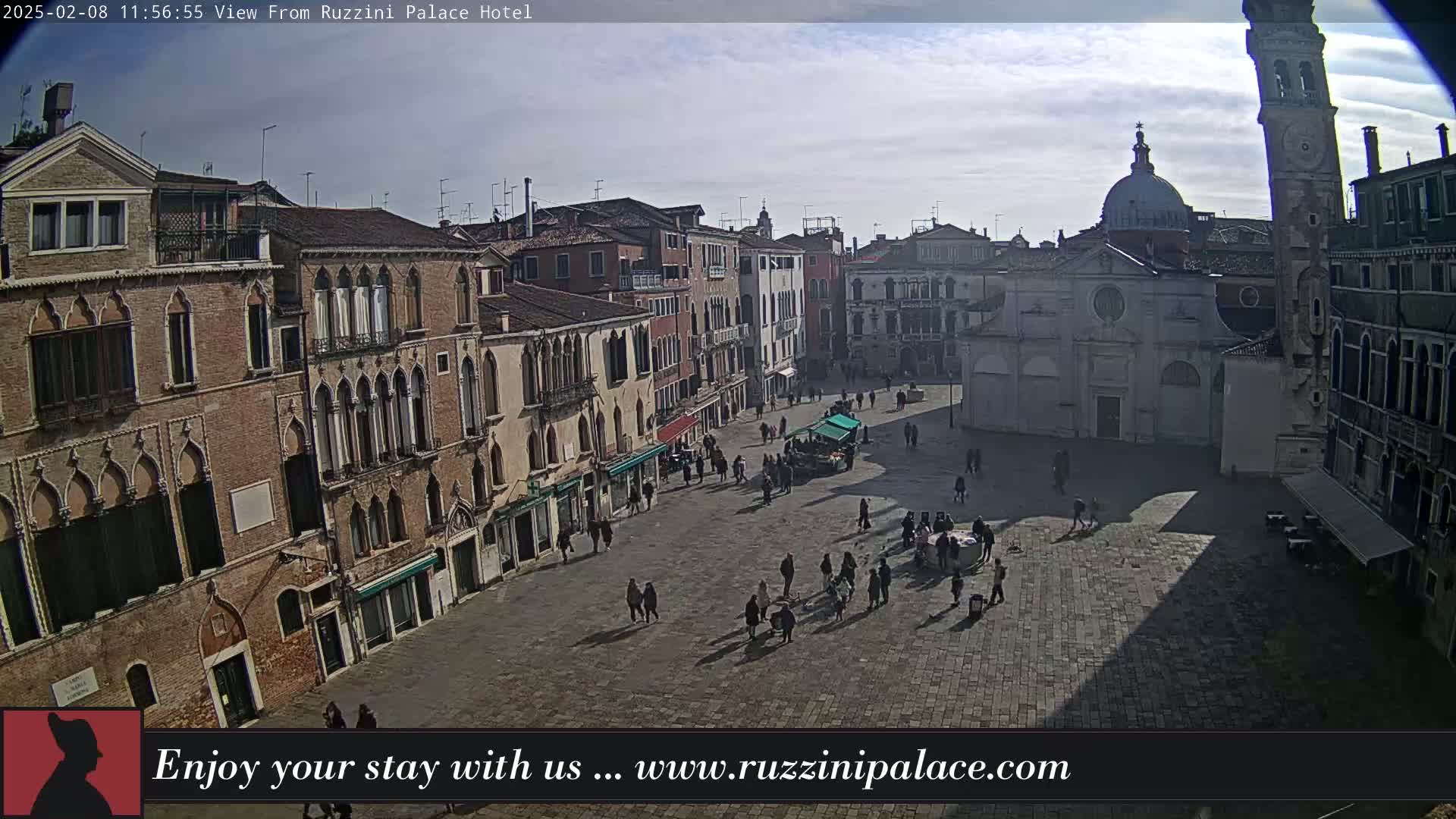 A mostly sunny day reveals a large, sparsely populated plaza in Venice, surrounded by historic buildings, including a church and a tall bell tower.