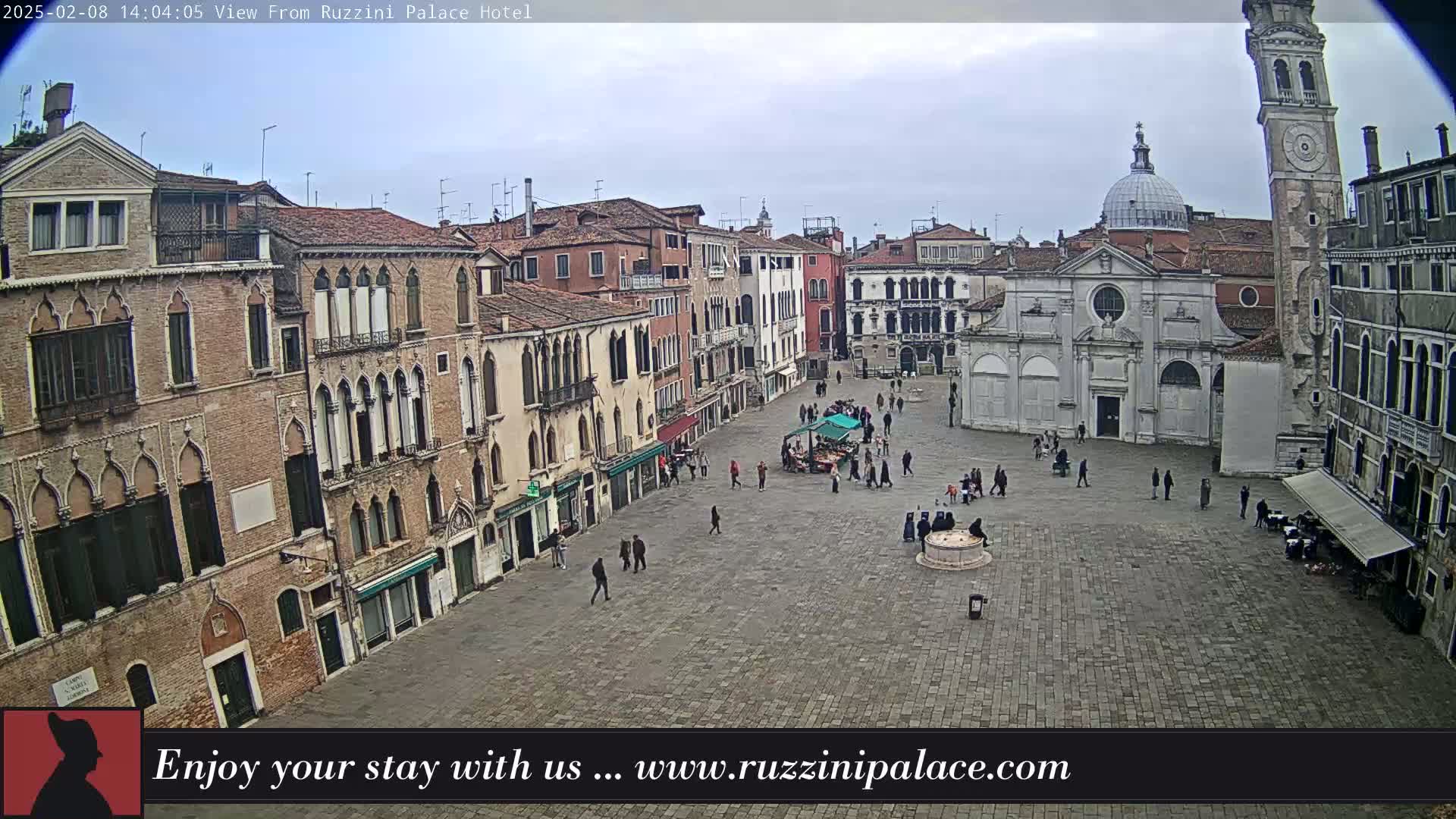 A mostly empty cobblestone square in Venice, Italy, is surrounded by historic buildings under an overcast sky.