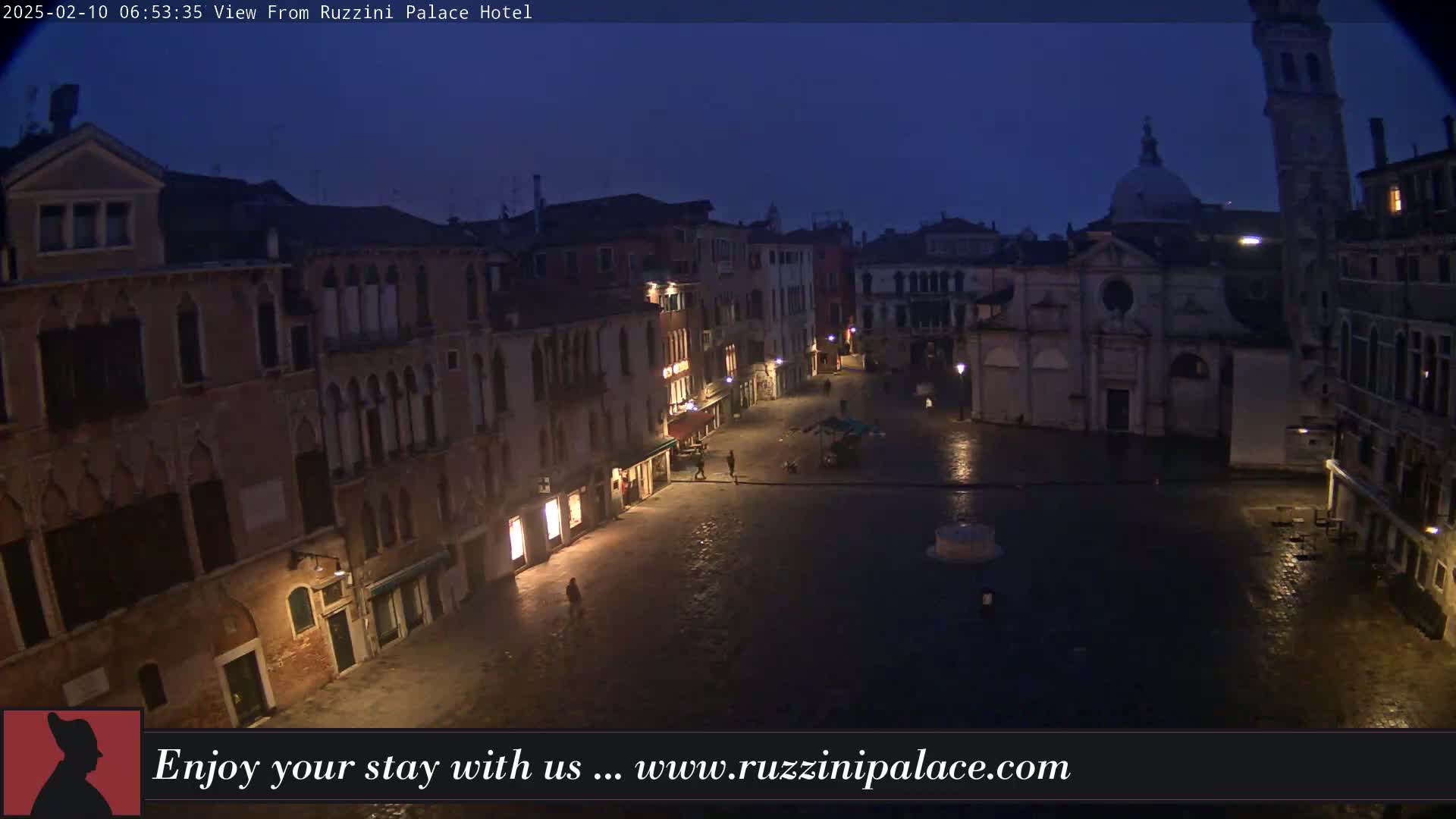 A dark, wet, cobblestone square in Venice, Italy, is surrounded by old buildings under a twilight sky.