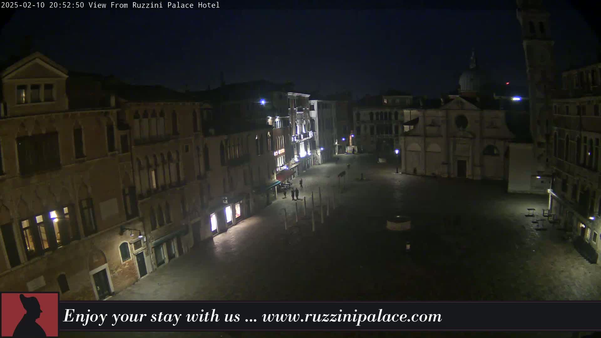 A nighttime, outdoor view of a dimly lit, empty square in Venice, surrounded by old buildings.
