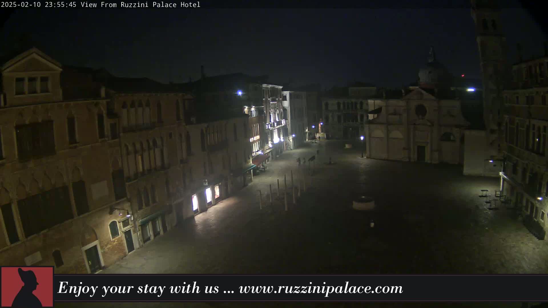 A nighttime view of a dimly lit, mostly empty square in Venice, surrounded by old buildings.
