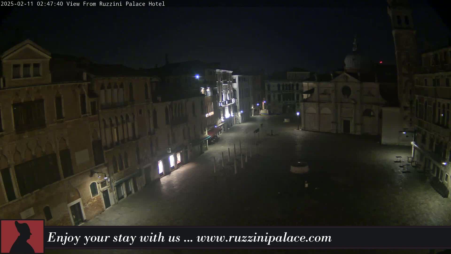 A nighttime view of a deserted plaza in Venice, Italy, surrounded by old buildings under a dark, clear sky.