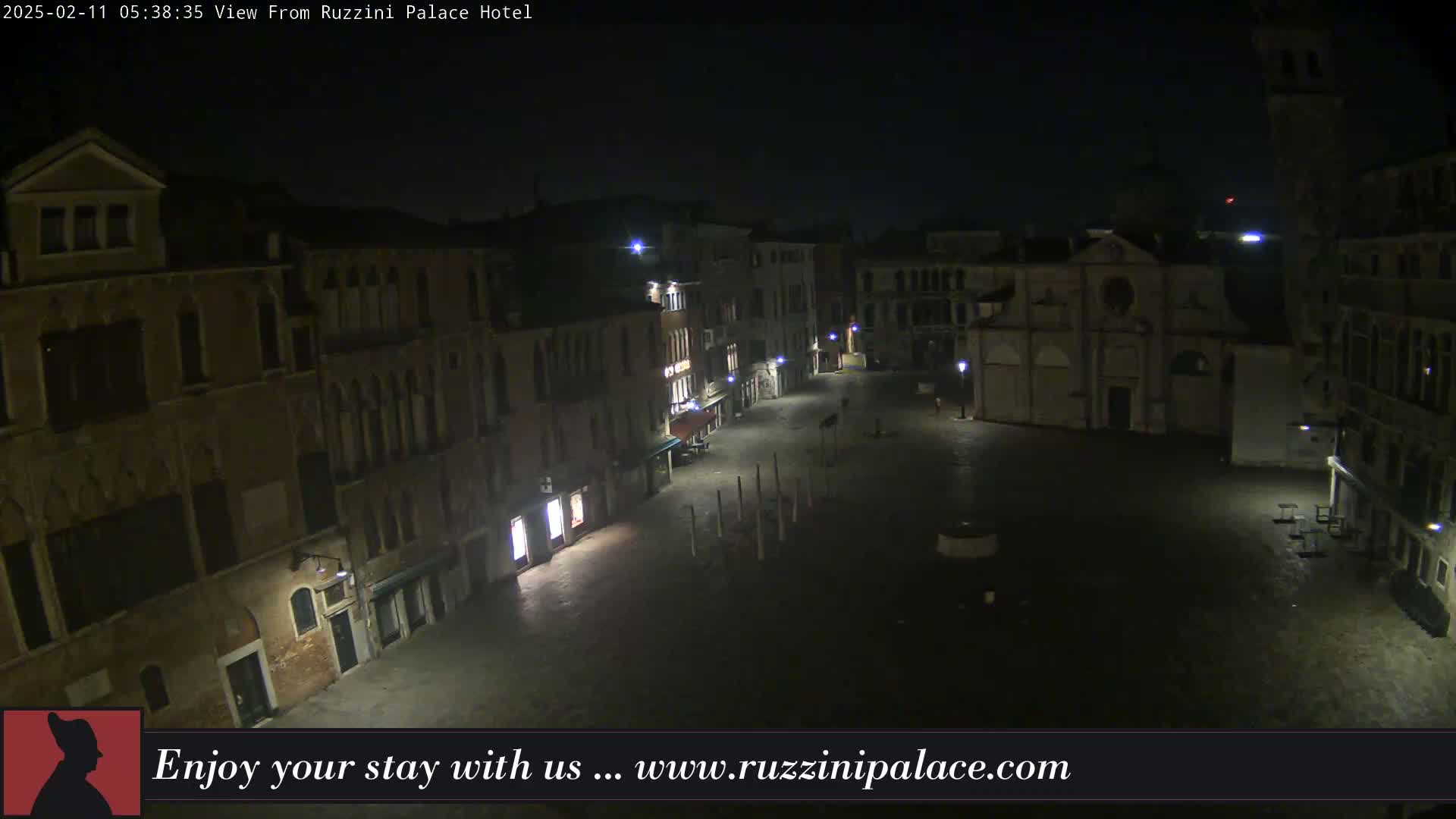 A nighttime, high-angle view of a dimly lit, empty square in Venice, surrounded by old buildings.