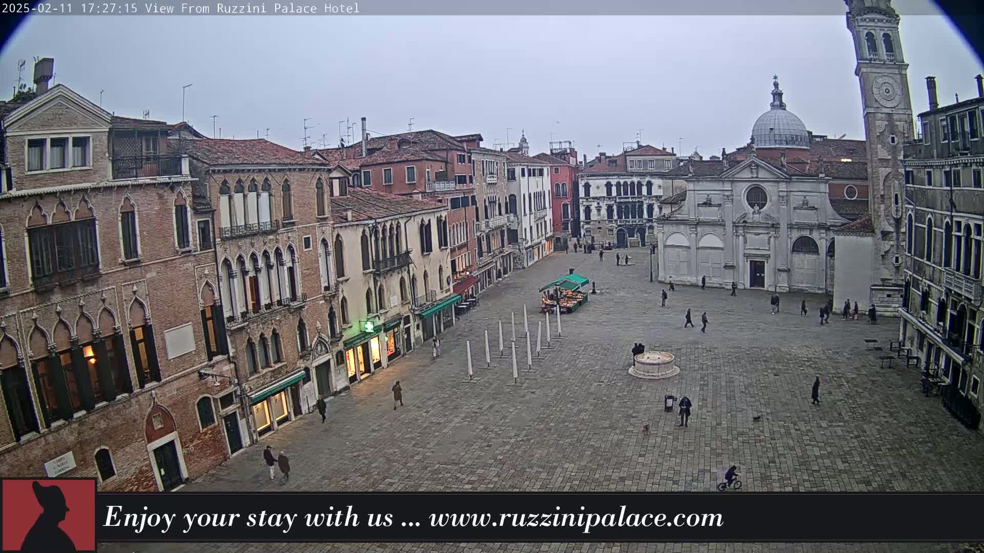A mostly empty cobblestone square in Venice, Italy, is surrounded by old buildings under an overcast sky.