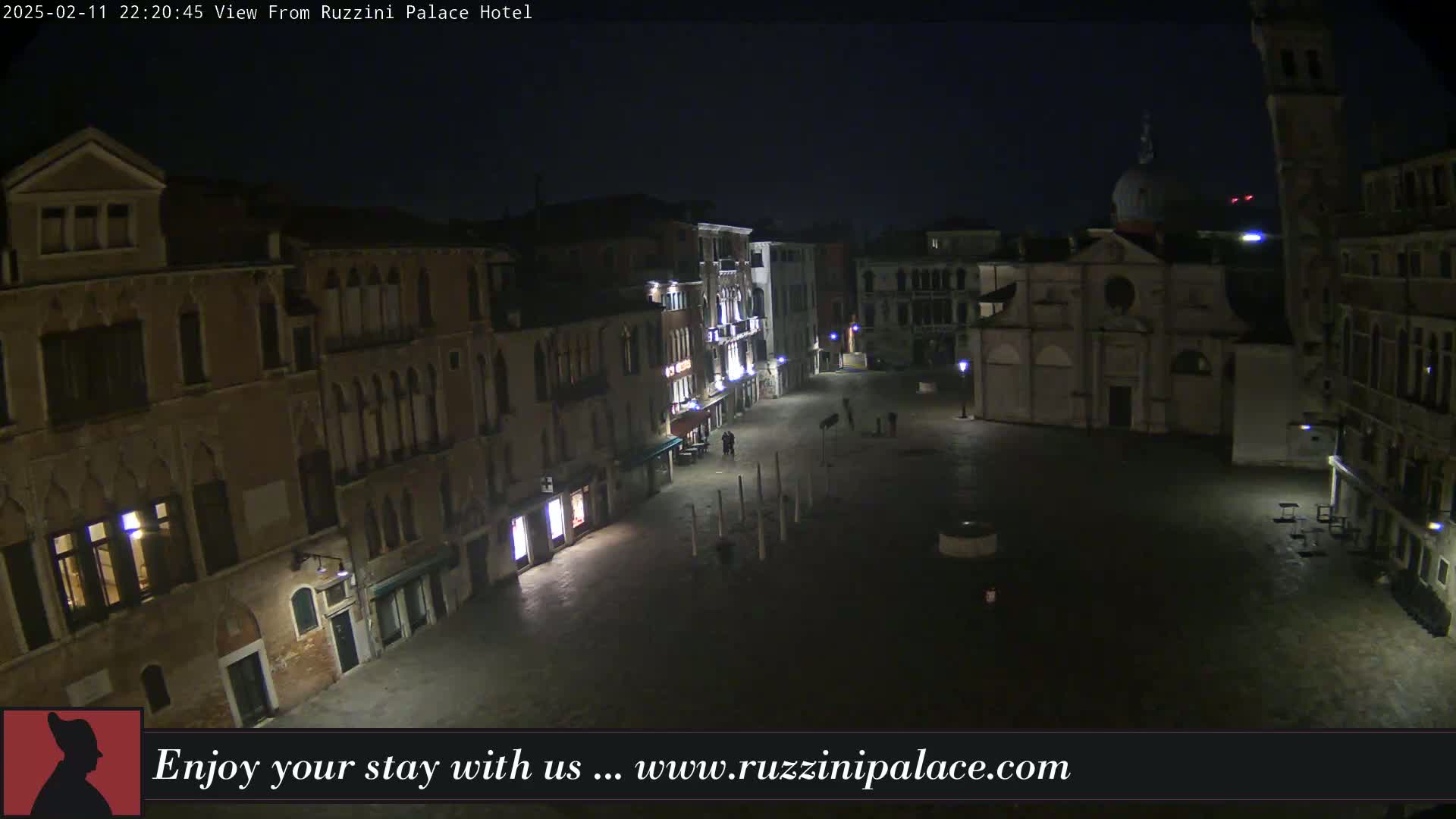 A nighttime, high-angle view of a dimly lit, empty Venetian piazza surrounded by old buildings.