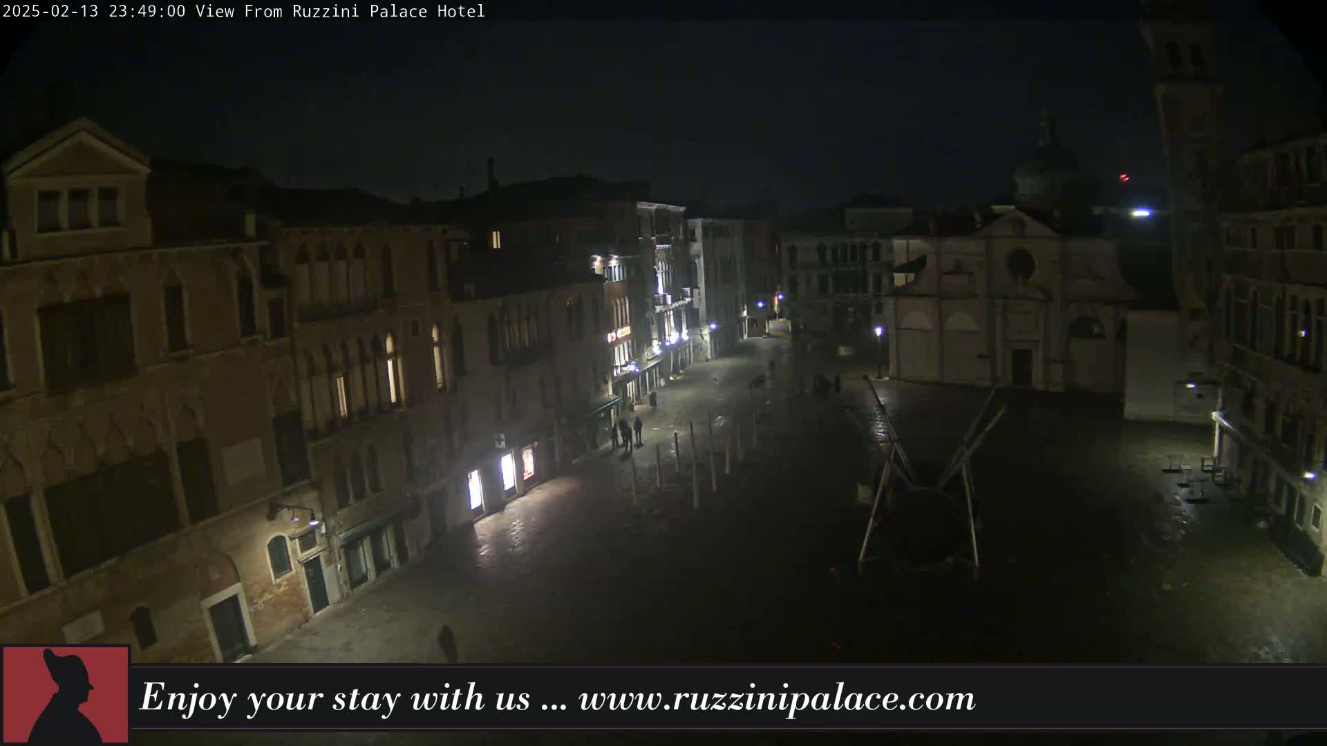 A nighttime view of a dimly lit, empty square in Venice, surrounded by old buildings under a dark sky.