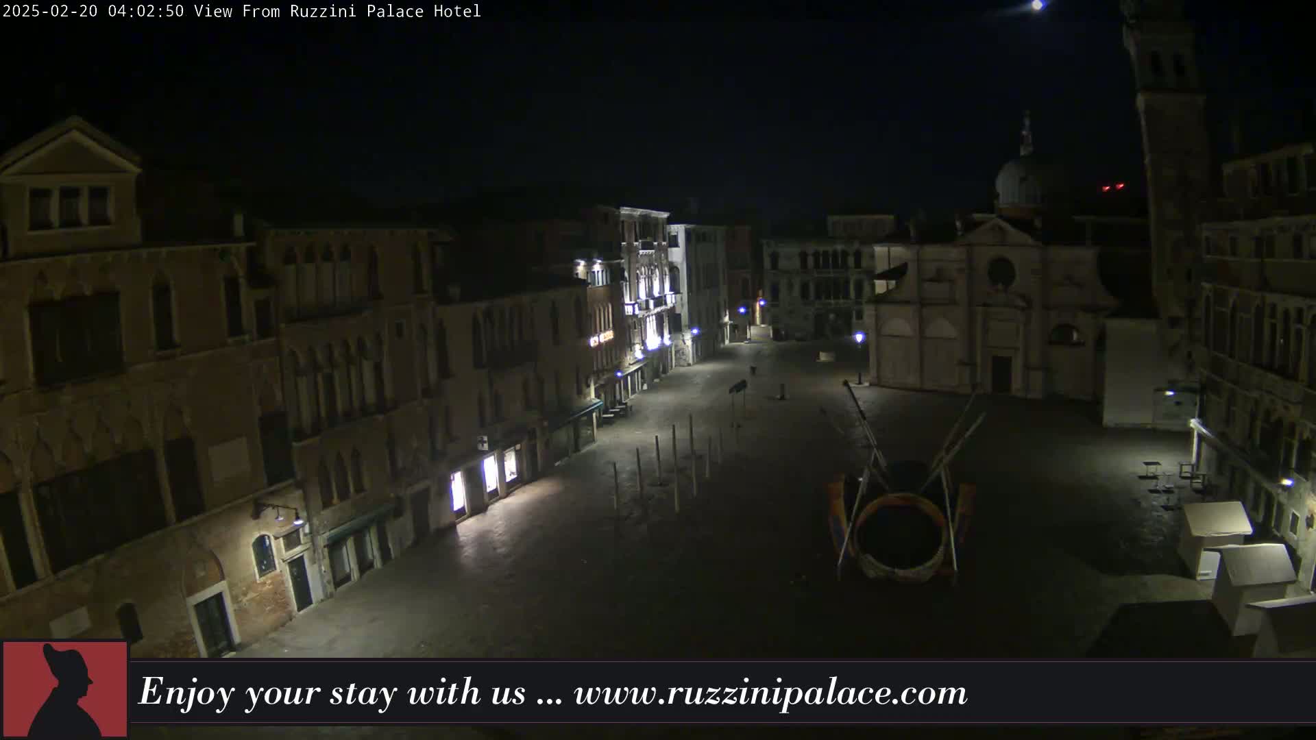 A nighttime view of a dimly lit, empty square in Venice, surrounded by old buildings under a clear sky.