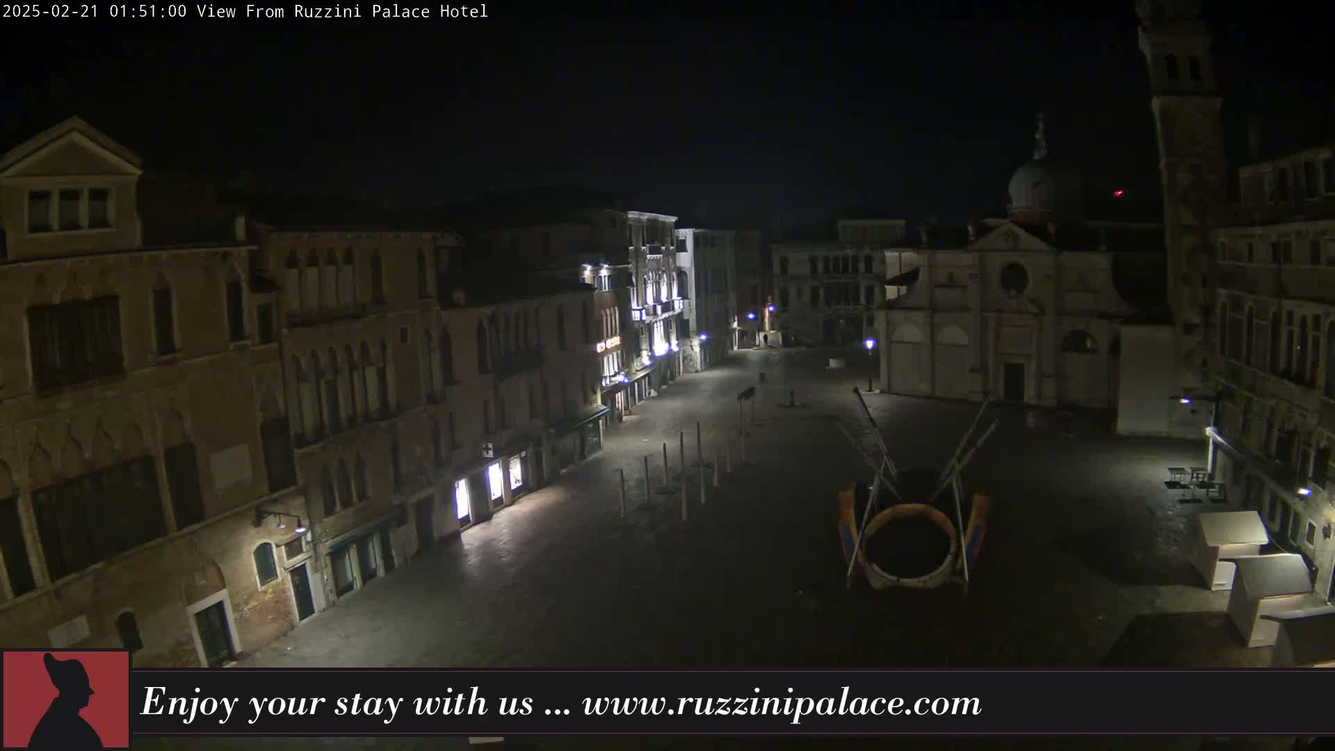 A nighttime view of a dark, empty plaza in Venice, Italy, surrounded by old buildings.