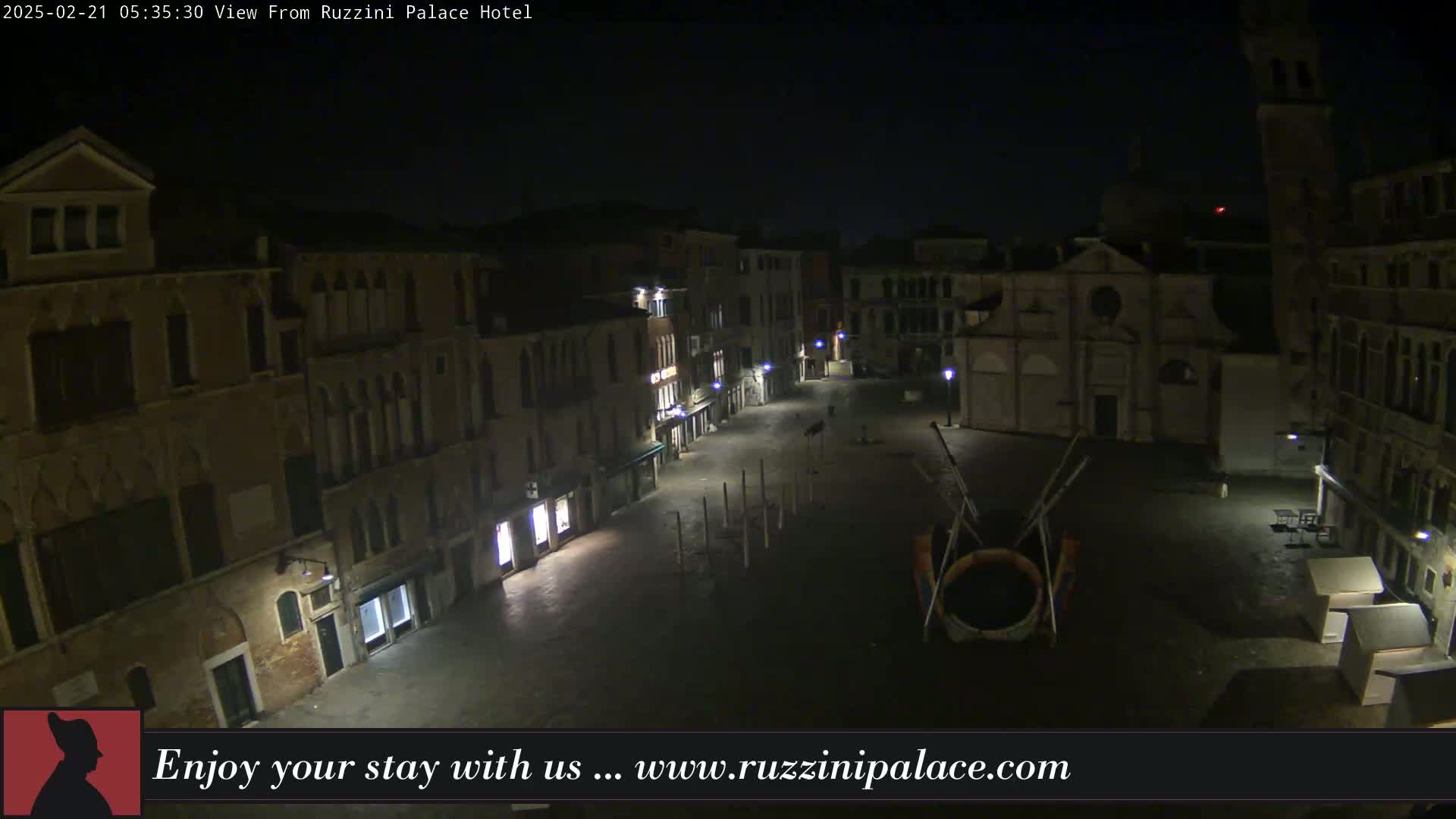 A nighttime, deserted Venetian square is shown, with old buildings lining its sides and a few lights illuminating the scene.