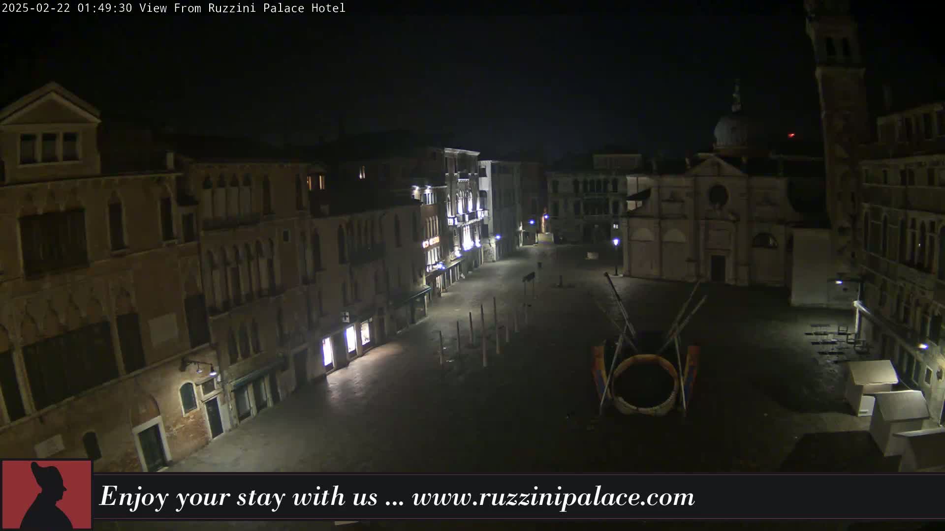 A nighttime, high-angle view of a dimly lit, empty square in Venice, surrounded by old buildings.